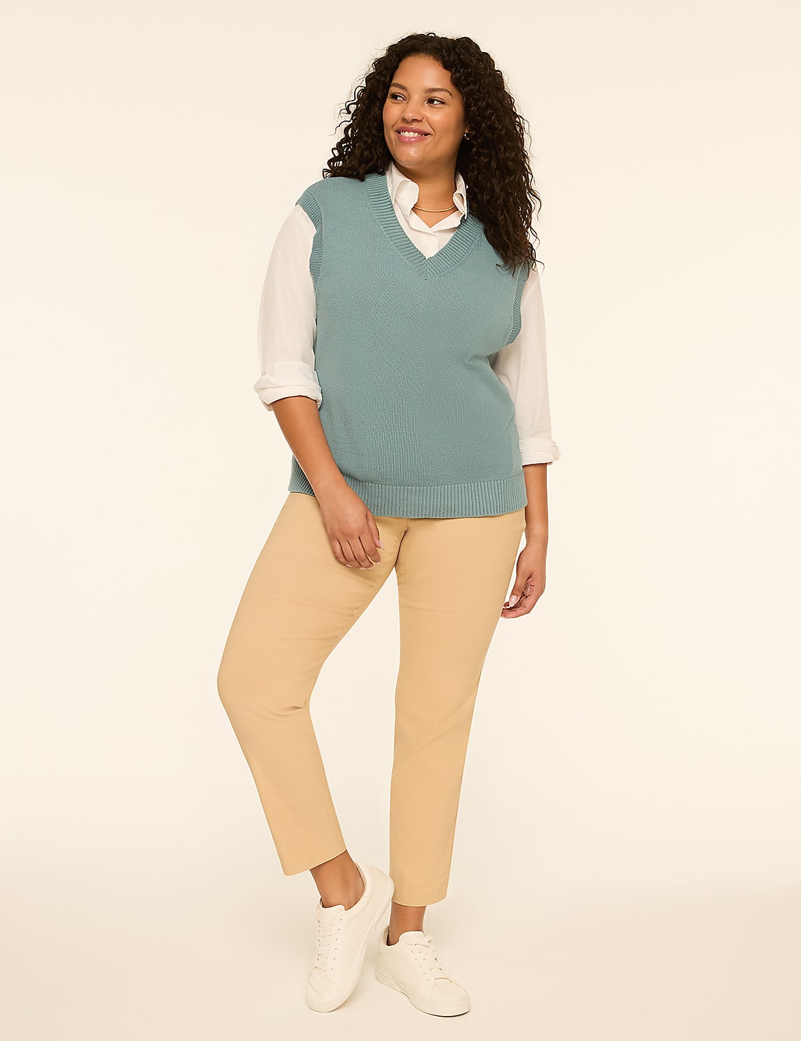 A woman in a teal sweater vest and tan pants stands against a plain, light background. Product Image 3