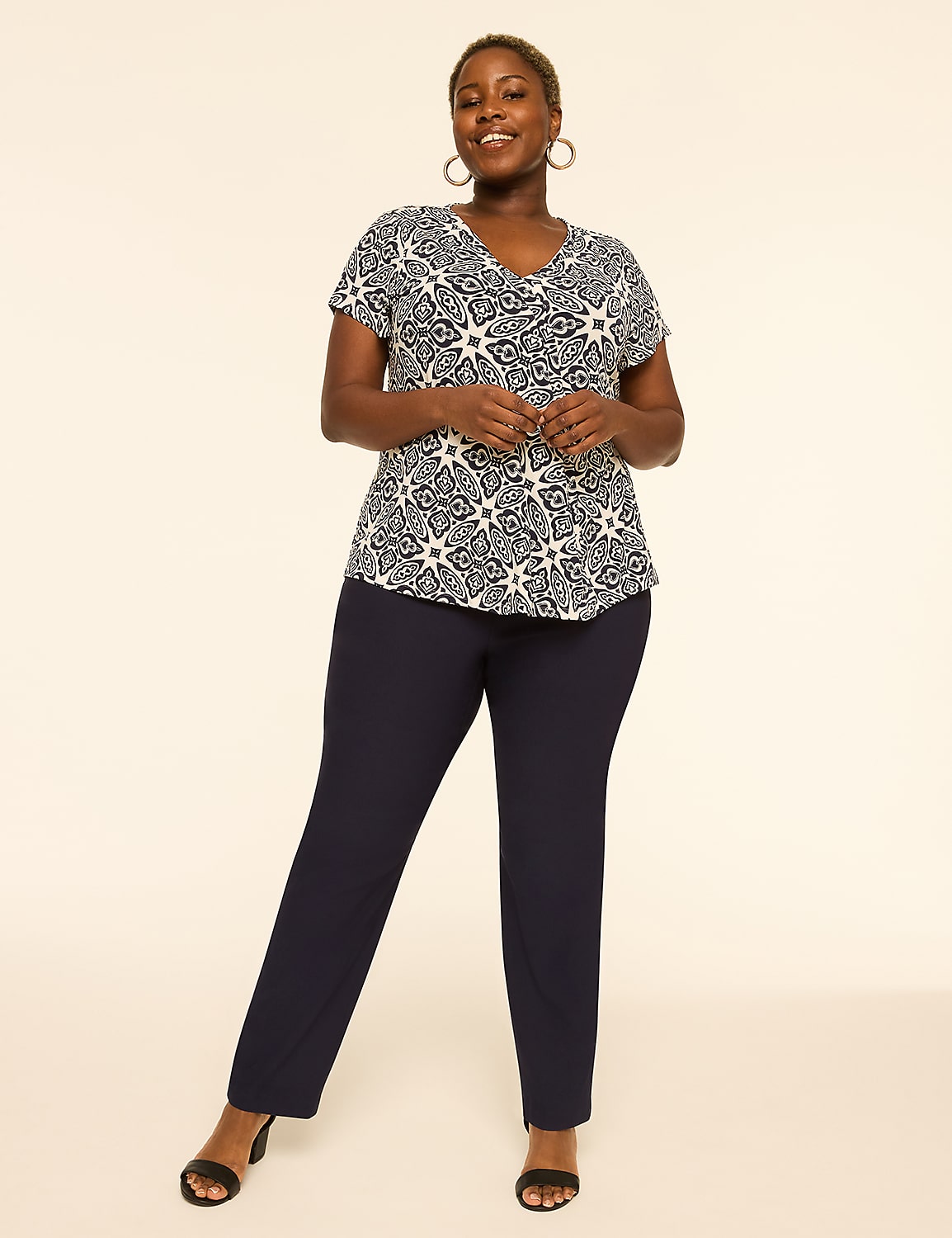 A smiling woman in a patterned top and navy pants stands against a plain, light-colored background. Product Image 3