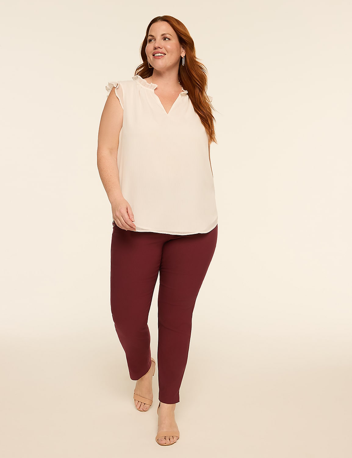 A woman in a cream-colored ruffled top and burgundy pants walks forward against a plain, light background. Product Image 3