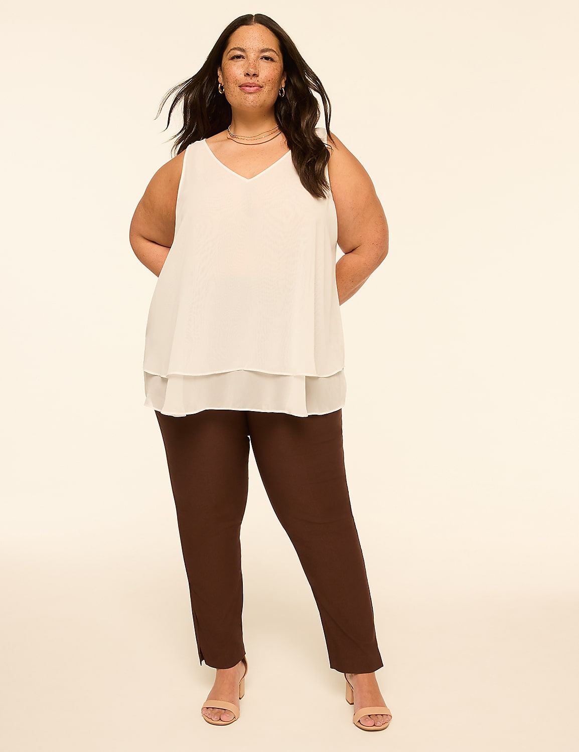 A woman in a white layered top and brown pants stands against a plain, light-colored background. Product Image 3