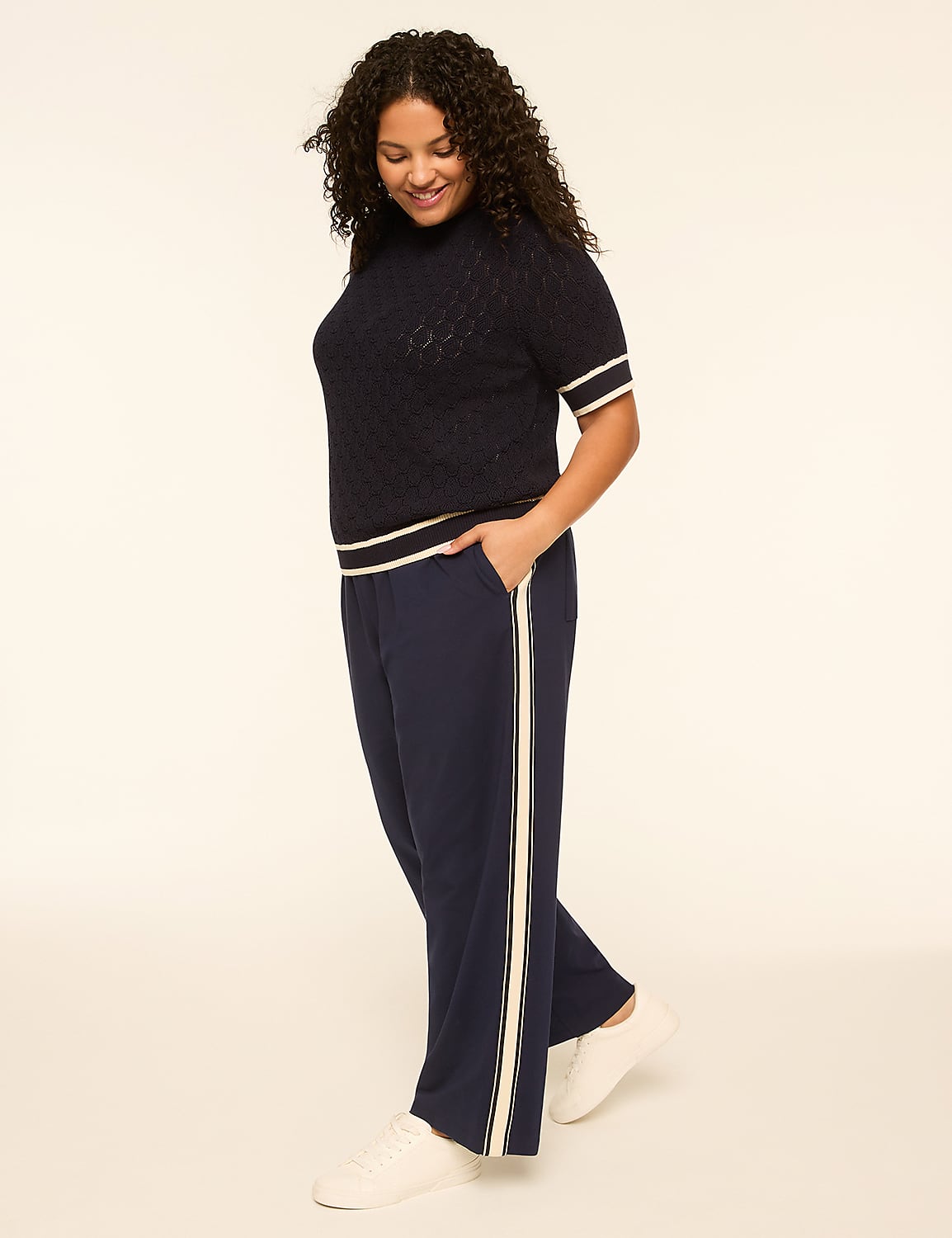 A woman in a navy blue top and matching pants with white stripes stands against a plain, light-colored background. Product Image 3