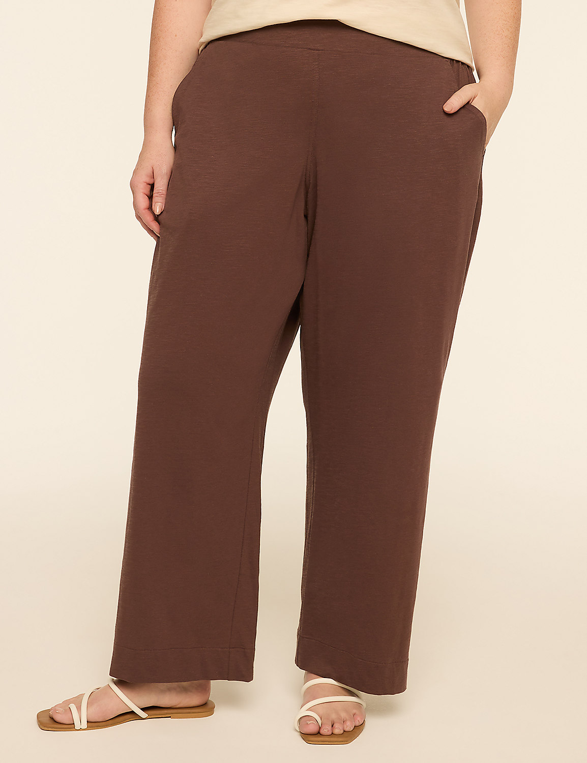 A person wearing brown pants and white sandals stands against a plain, light-colored background. Product Image 1