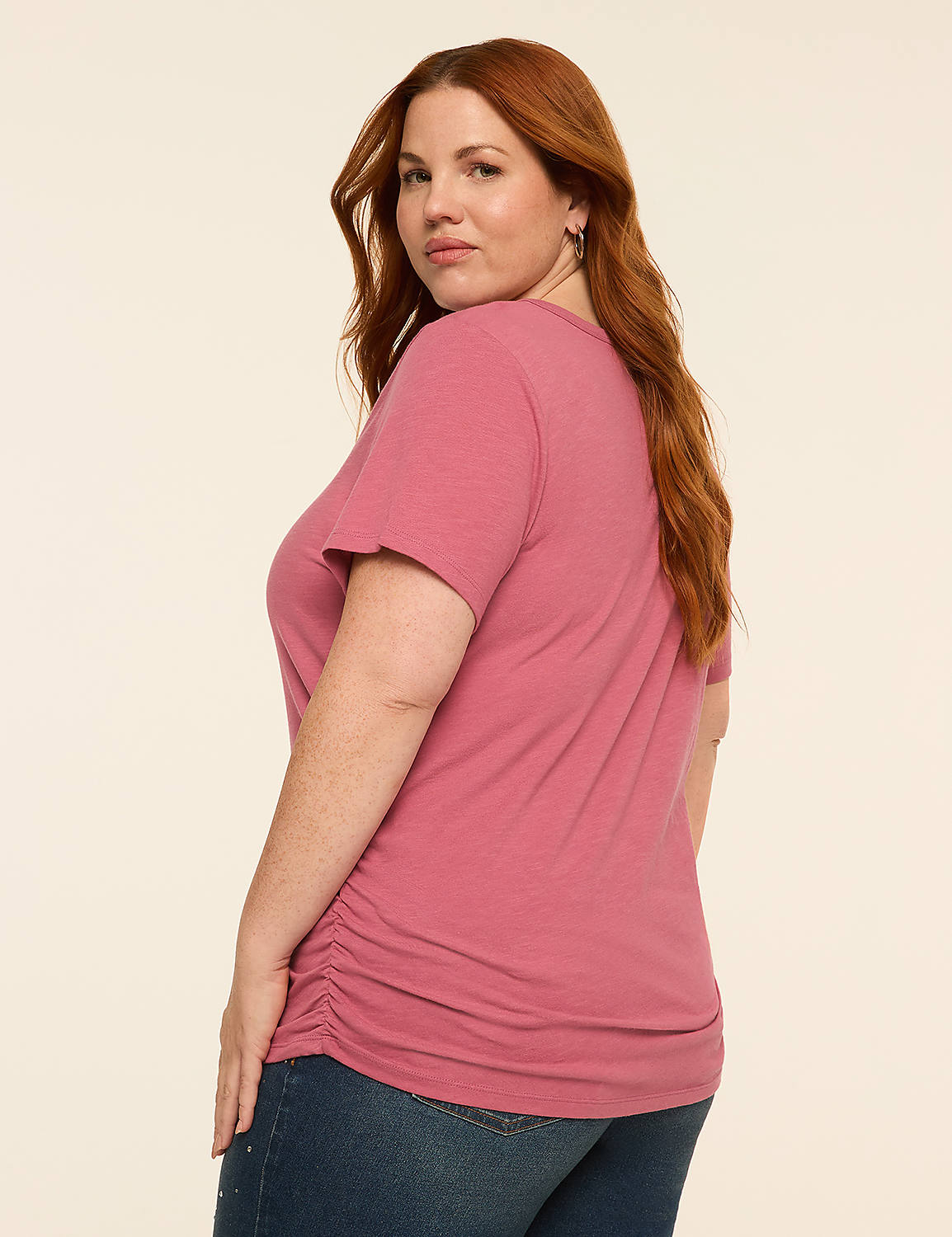 A woman with red hair in a pink t-shirt and jeans stands against a plain beige background. Product Image 2