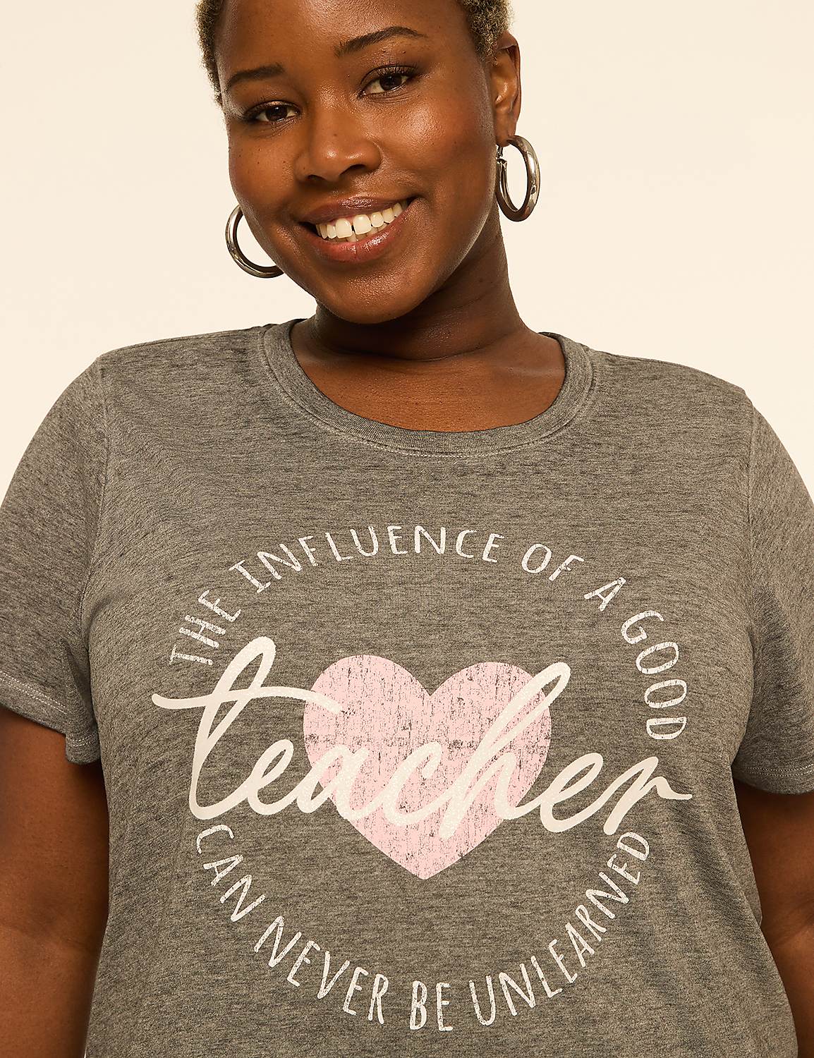 A smiling woman in a grey t-shirt with a teacher-themed graphic stands against a plain, light-colored background. Product Image 4
