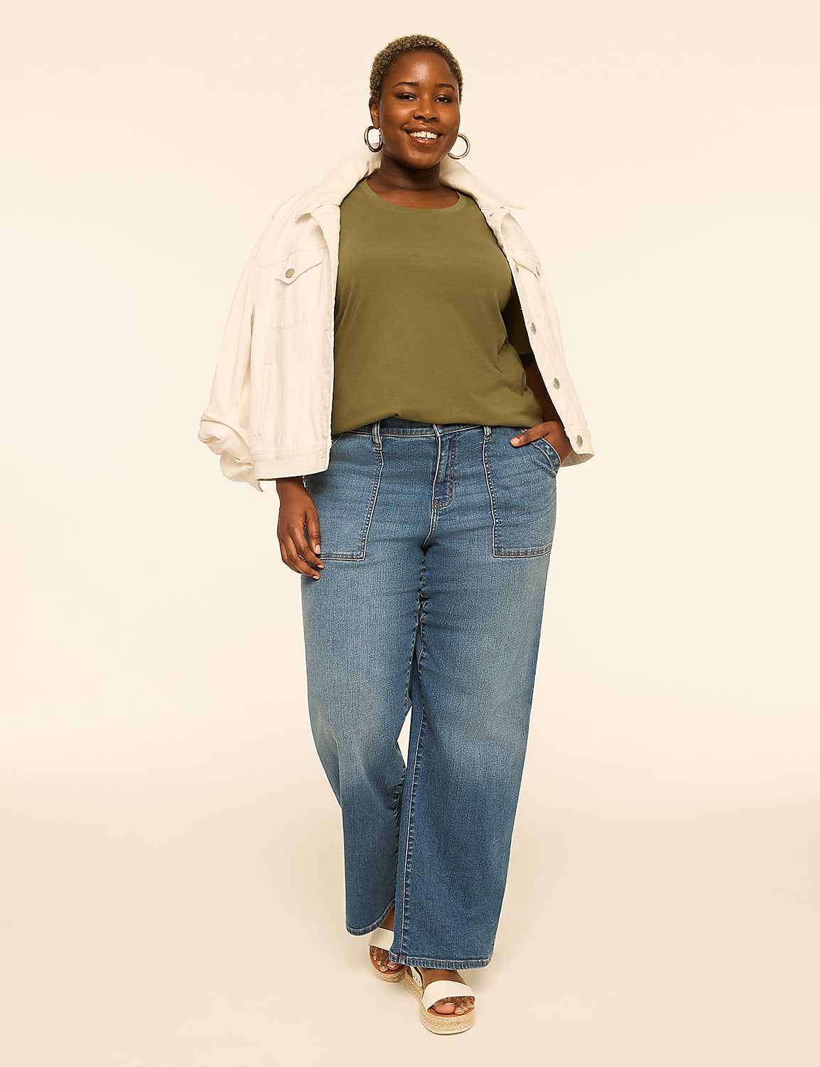 A smiling woman in a green shirt, white jacket, and wide-leg jeans stands against a plain, light-colored background. Product Image 3