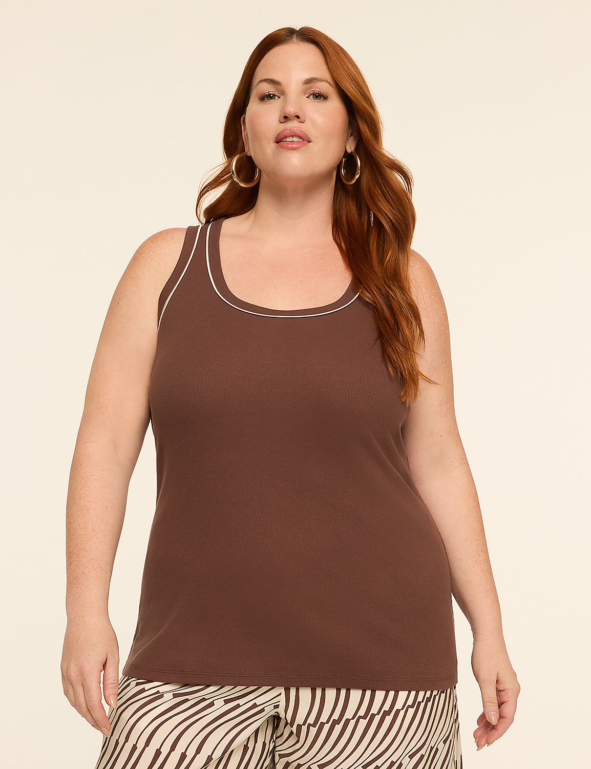 A woman with auburn hair and hoop earrings poses in a brown ribbed tank top with white trim, against a plain, light-colored background. Product Image 1