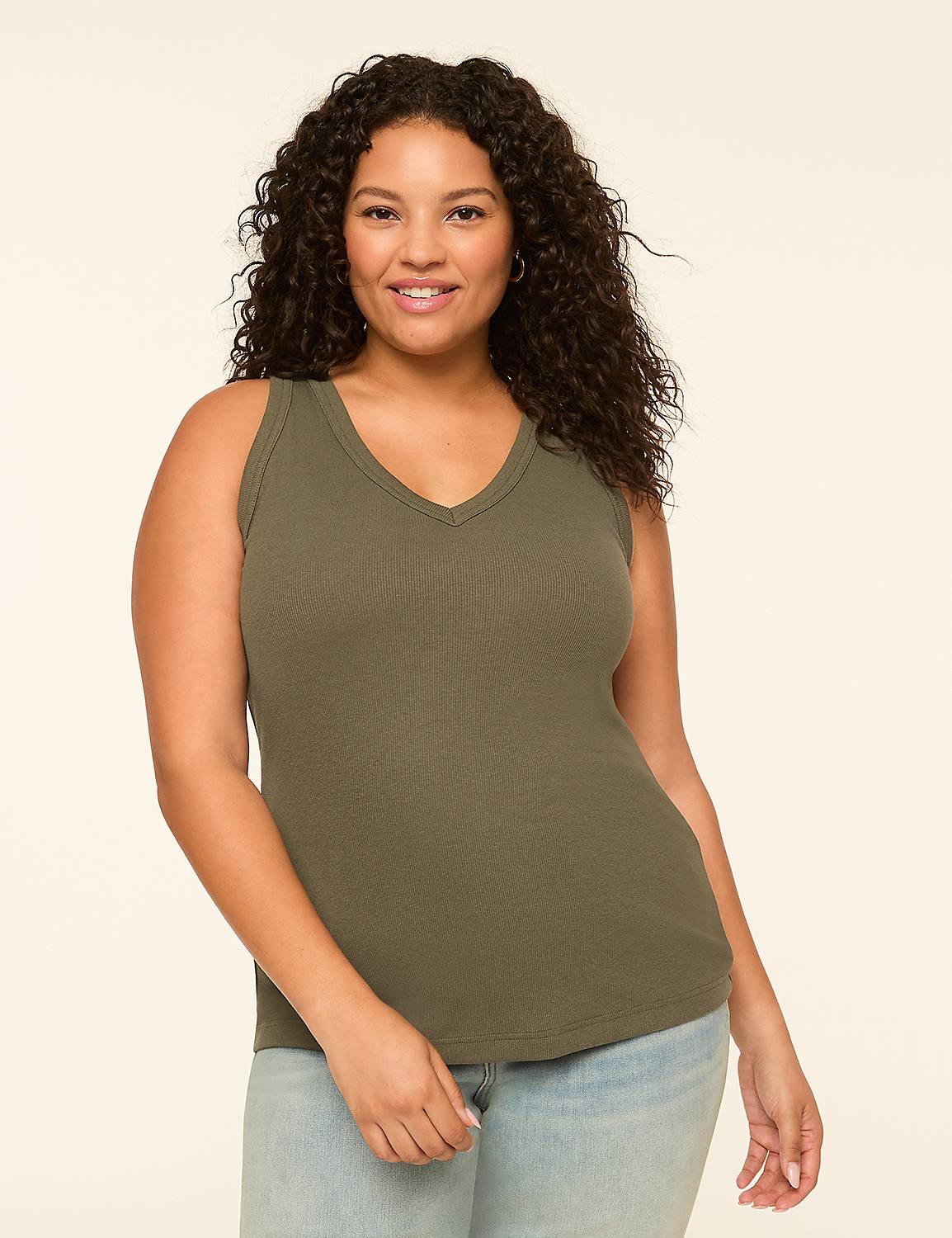 A smiling woman with curly dark hair wears a green ribbed tank top and light blue jeans against a plain cream background. Product Image 1