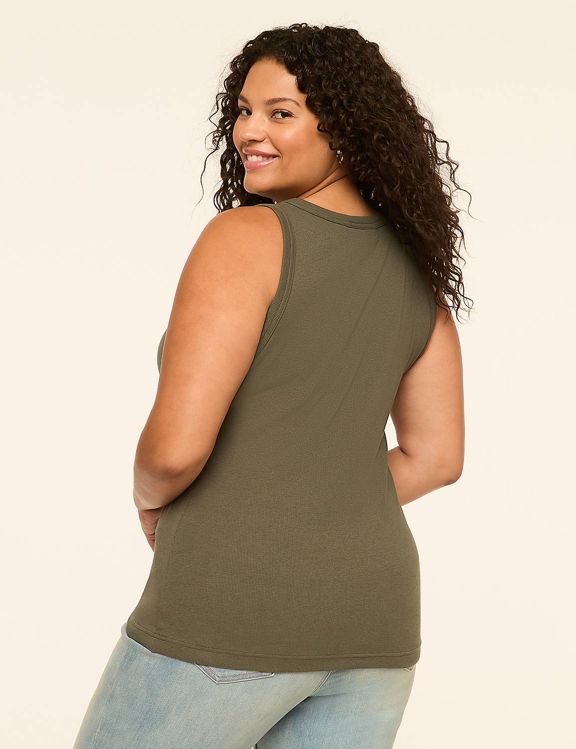 A woman in a green ribbed tank top and light blue jeans smiles over her shoulder against a plain cream background. Product Image 2