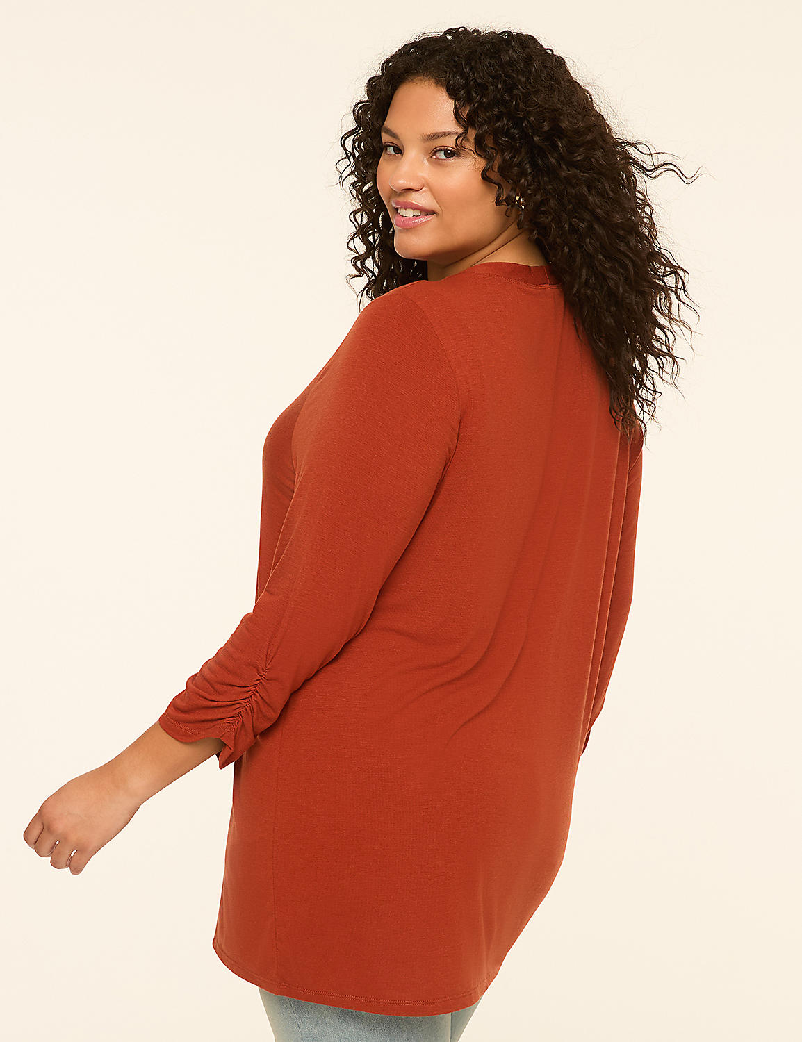 A woman with curly dark hair in a rust-colored tunic poses against a plain, light-colored background. Product Image 2