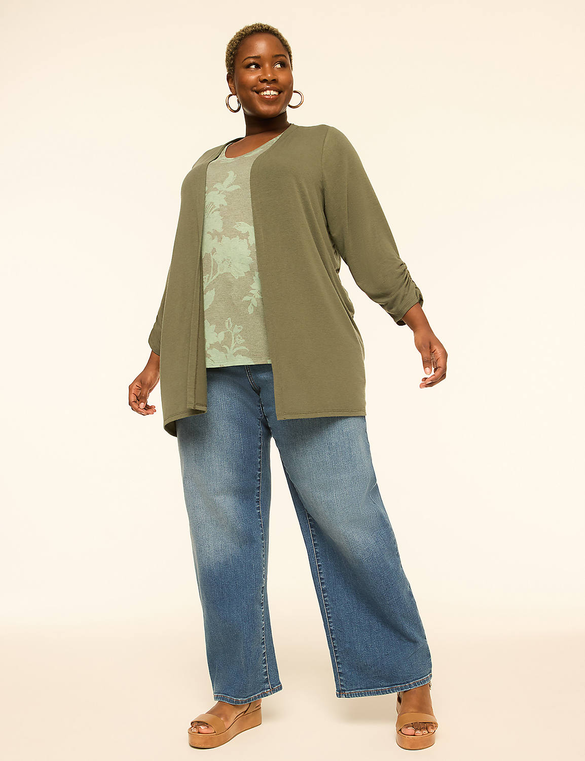 A smiling woman in a green cardigan and floral top stands in front of a plain, light-colored background. Product Image 3