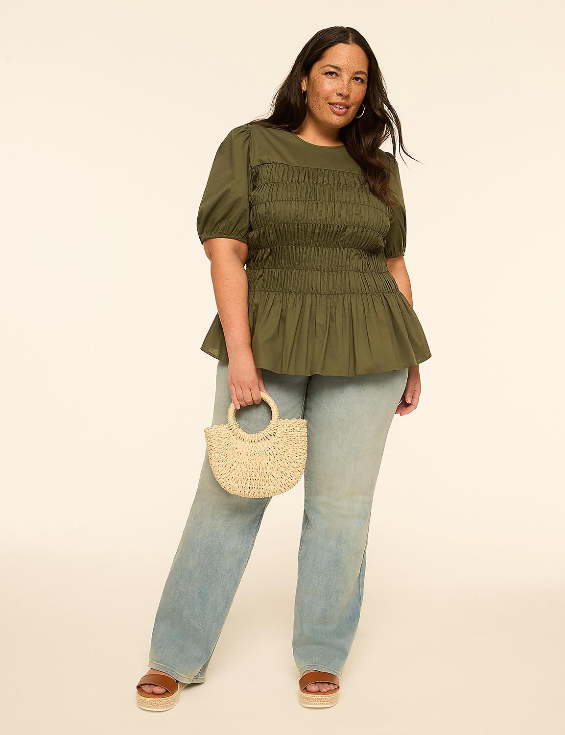 A woman in a green smocked top and light wash jeans holds a straw bag in front of a plain, light-colored background. Product Image 3
