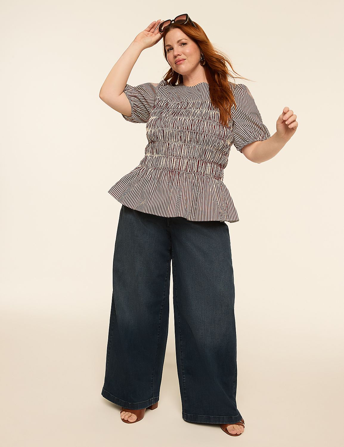 A woman with red hair in a smocked, striped top and wide-leg jeans poses against a plain, light-colored background. Product Image 3