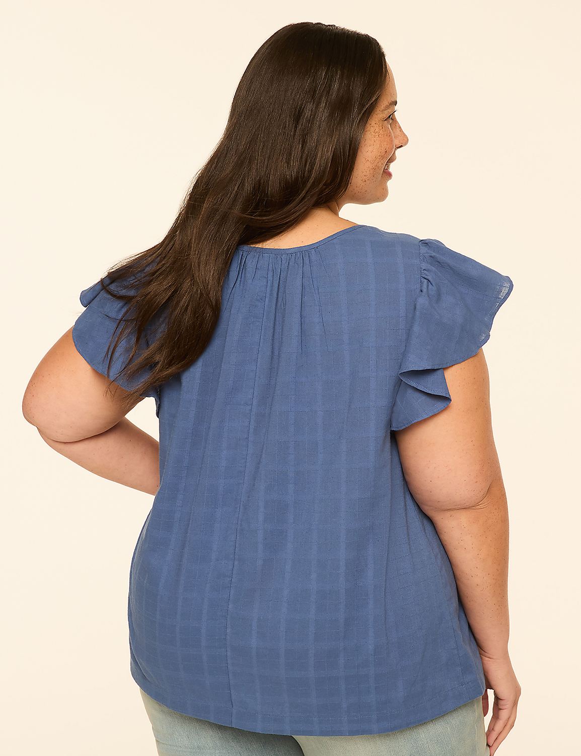 A woman in a blue, textured top with flutter sleeves is shown from the back against a plain, light-colored background. Product Image 2