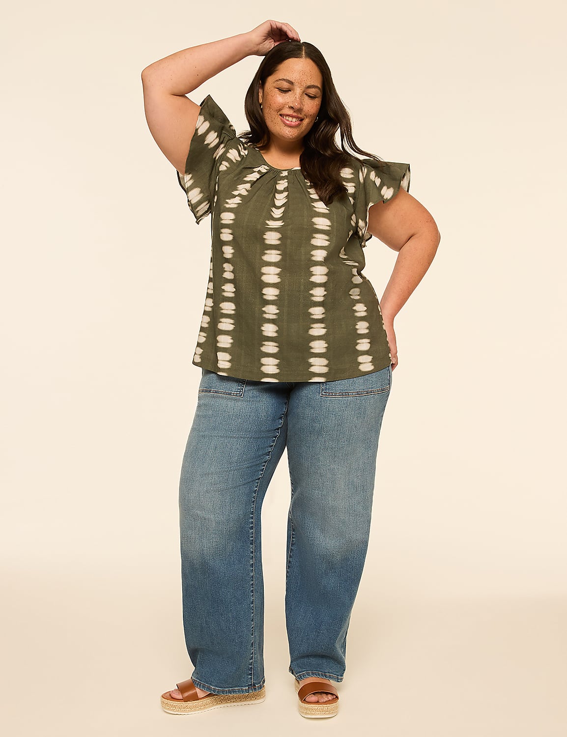 A woman in a green tie-dye top and wide-leg jeans poses against a plain, light-colored background. Product Image 3
