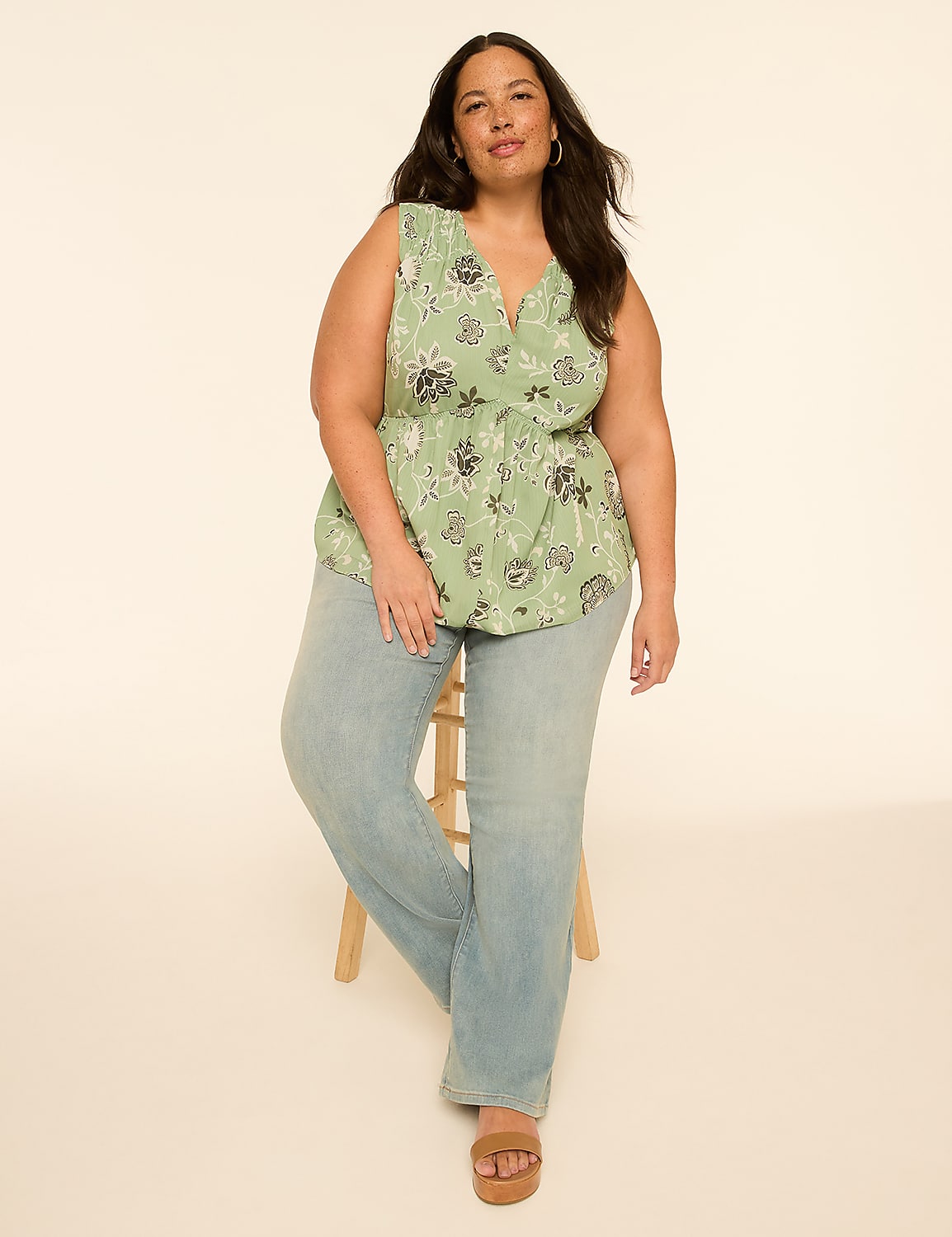 A woman in a floral top and jeans sits on a stool against a plain, light-colored background. Product Image 3