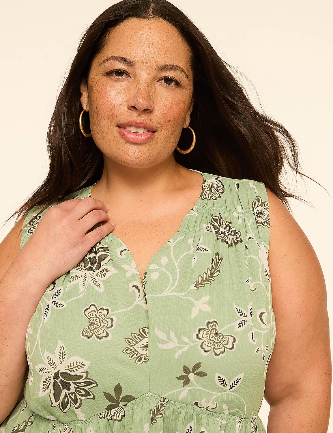 A woman with freckles and hoop earrings smiles at the camera, wearing a light green floral print dress against a plain, light background. Product Image 4