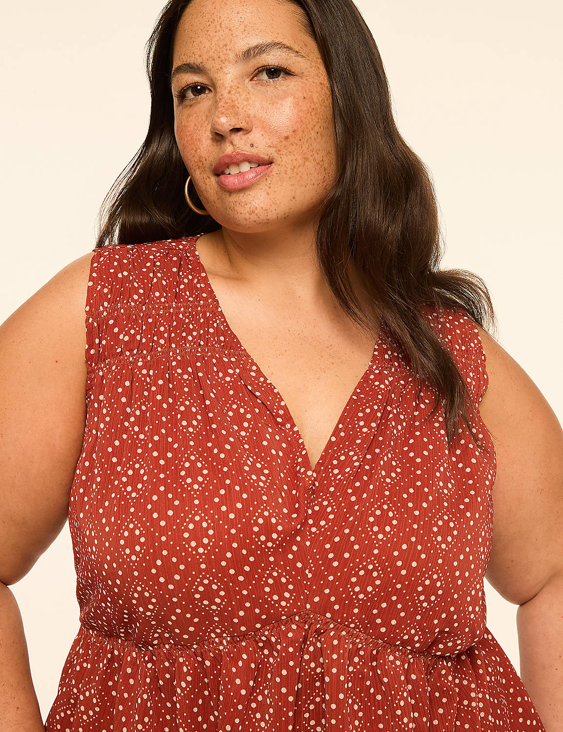 A woman with freckles and dark hair in a rust-colored patterned top smiles against a plain, light background. Product Image 4