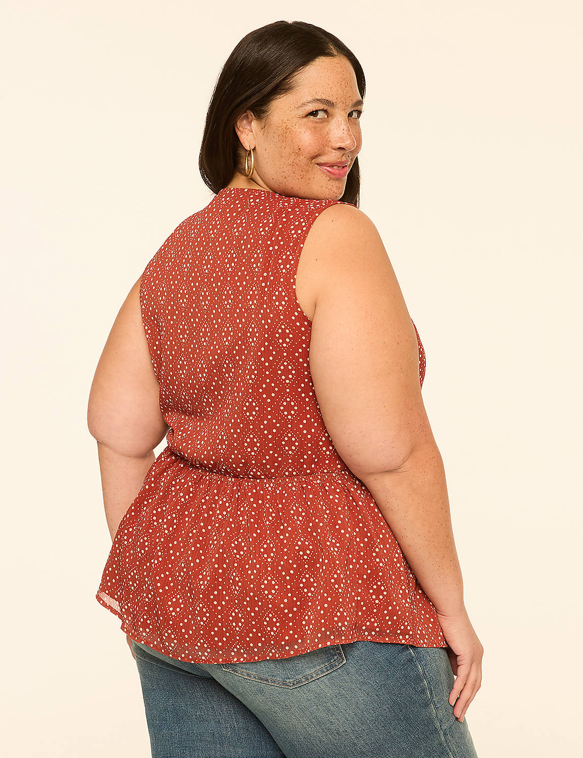 A woman in a patterned rust-colored top and blue jeans poses against a plain, light-colored background. Product Image 2