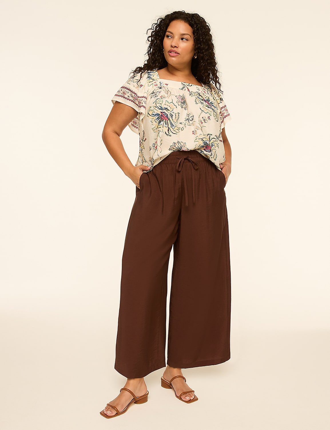 A woman in a patterned top and brown wide-leg pants stands against a plain, light-colored background. Product Image 4