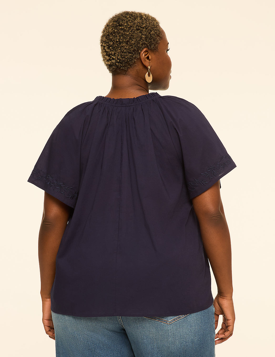 A woman in a navy blue top and jeans stands against a plain, light-colored background. Product Image 2