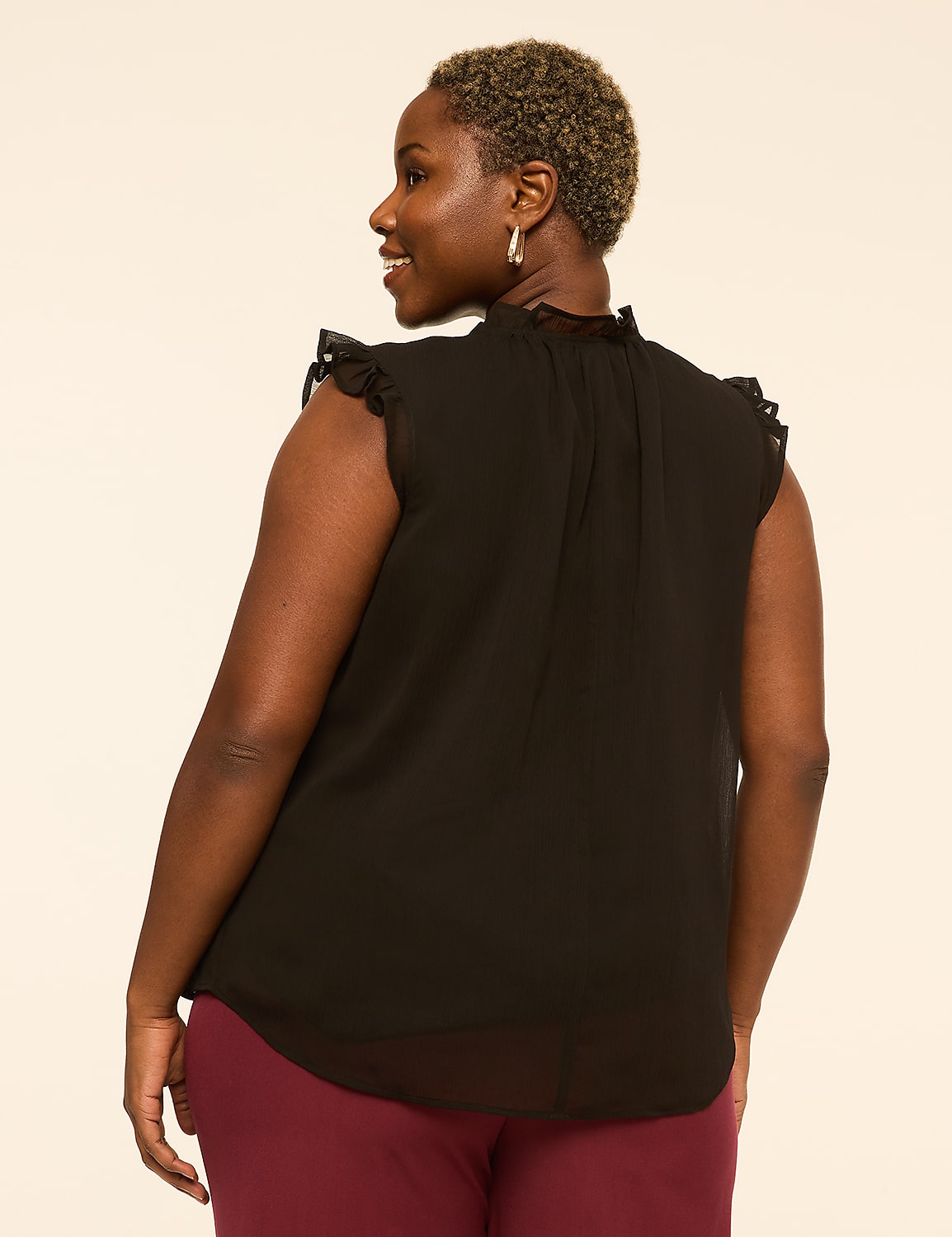 A woman in a black ruffled-sleeve blouse and maroon pants stands against a plain, light-colored background. Product Image 2