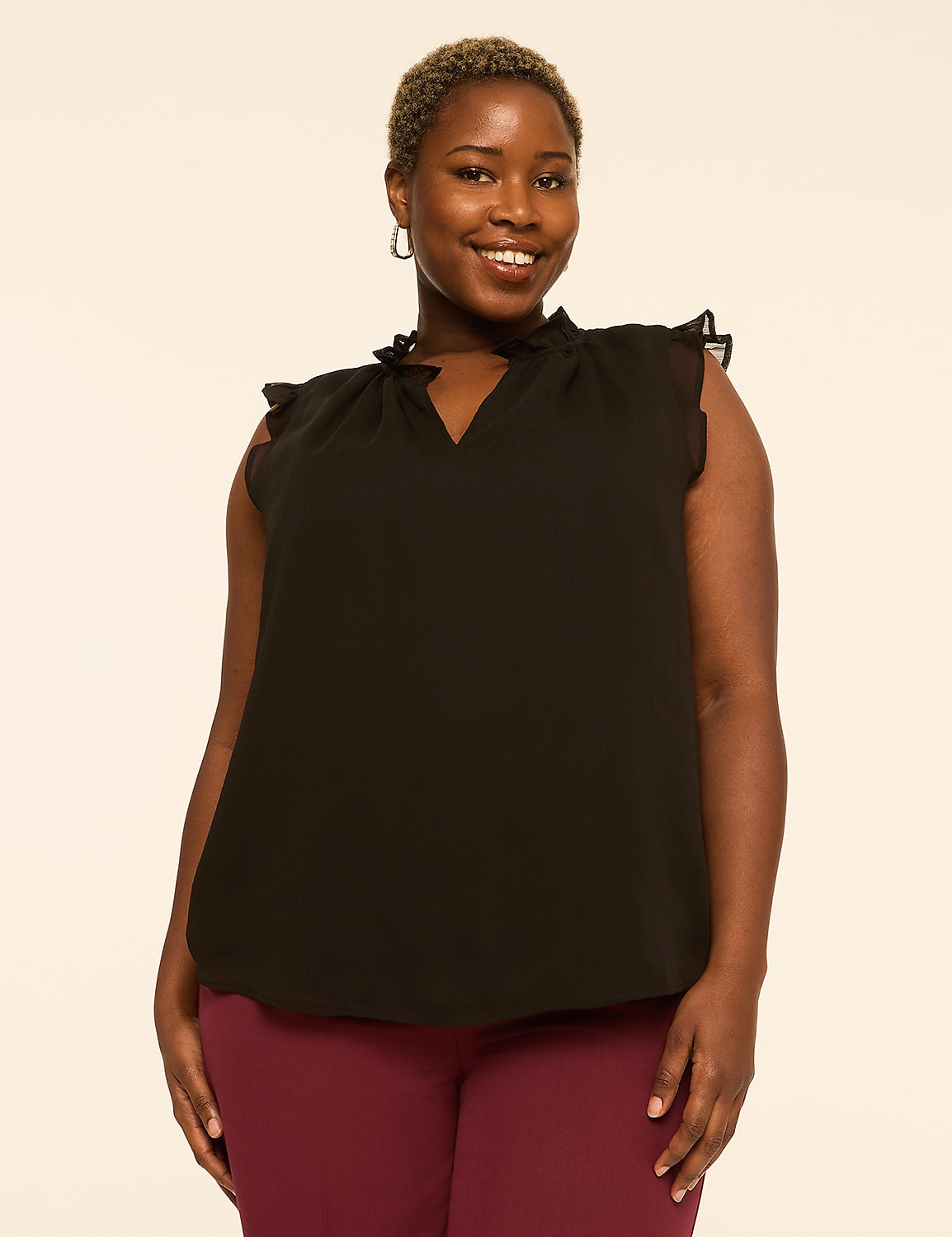 A smiling woman with short hair wears a black ruffled blouse and maroon pants against a plain, light-colored background. Product Image 1