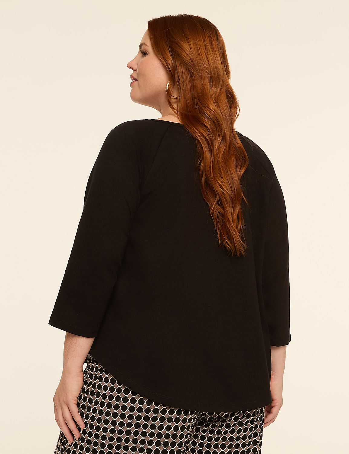 A woman with red hair, wearing a black top and patterned pants, stands against a plain, light-colored background. Product Image 2