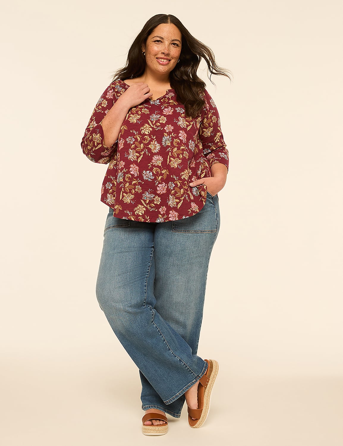 A smiling woman in a floral top and wide-leg jeans stands against a plain, light-colored background. Product Image 3