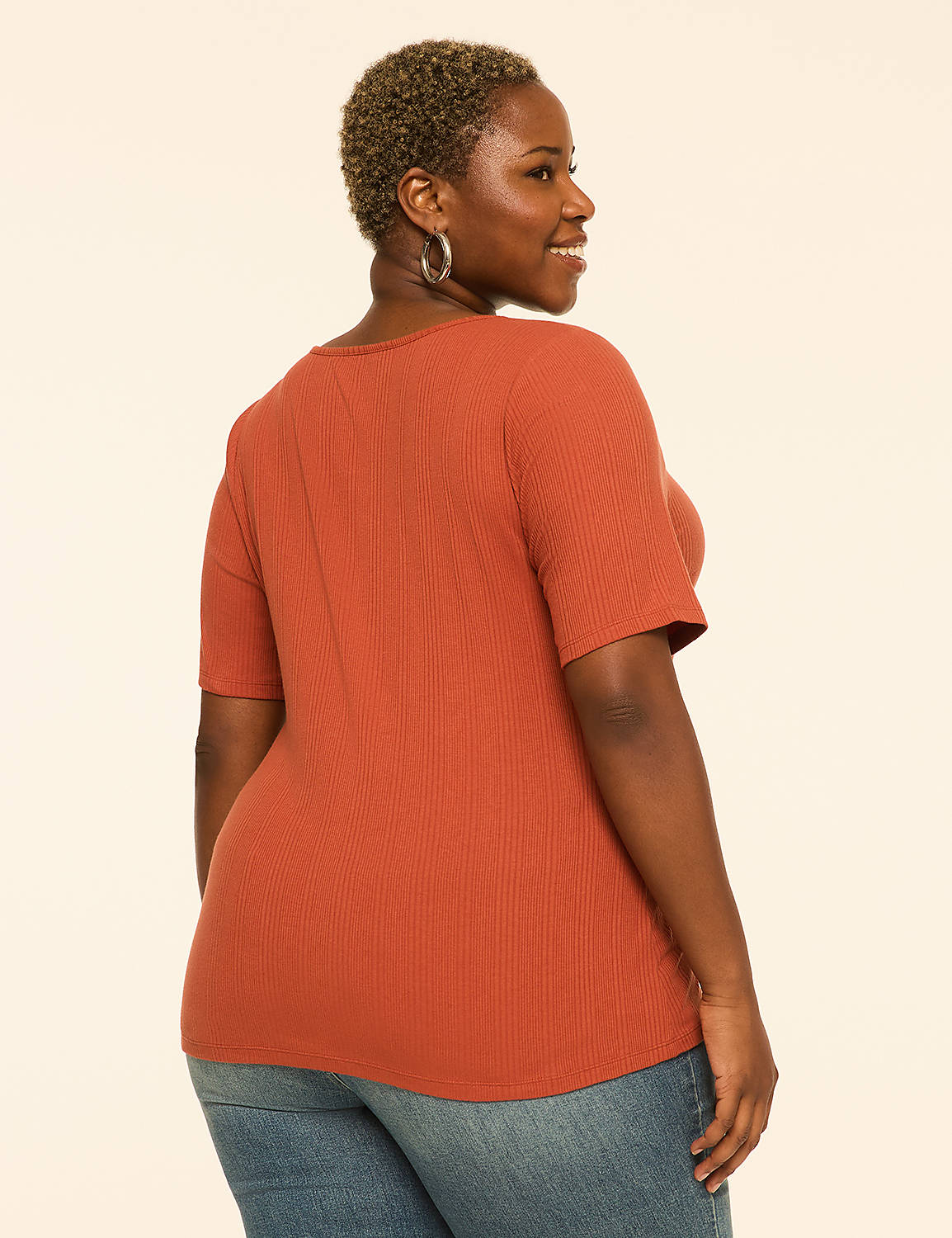 A woman in a rust-colored ribbed shirt and blue jeans stands against a plain, light-colored background. Product Image 2