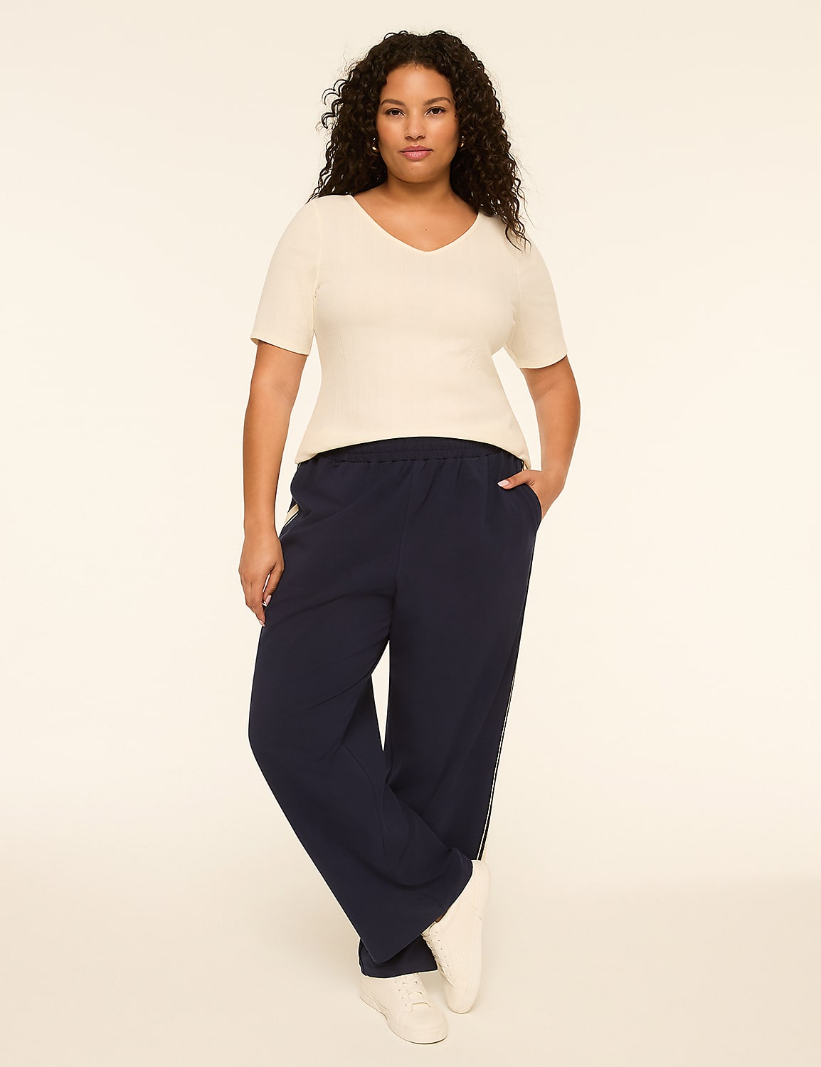 A woman in a cream top and navy pants stands against a plain, light background. Product Image 3