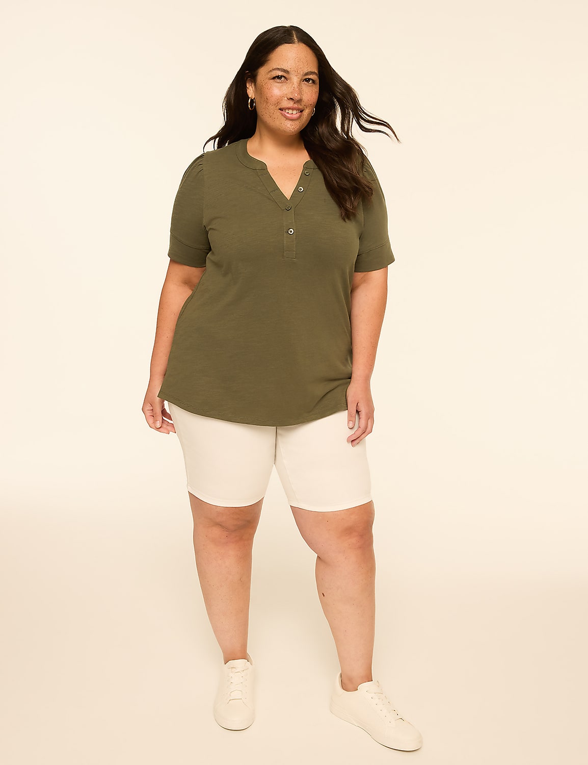 A woman in a green shirt and white shorts stands against a plain, light-colored background. Product Image 3