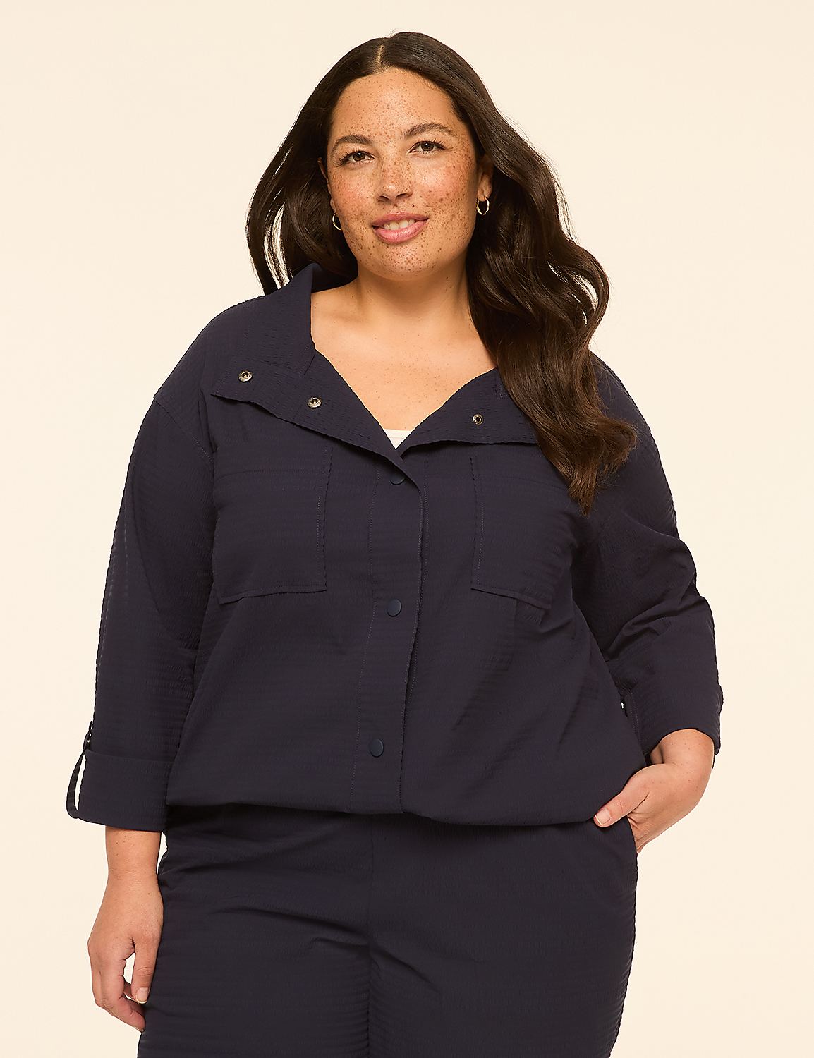 A woman in a navy blue textured jacket and pants stands against a plain cream background. Product Image 1