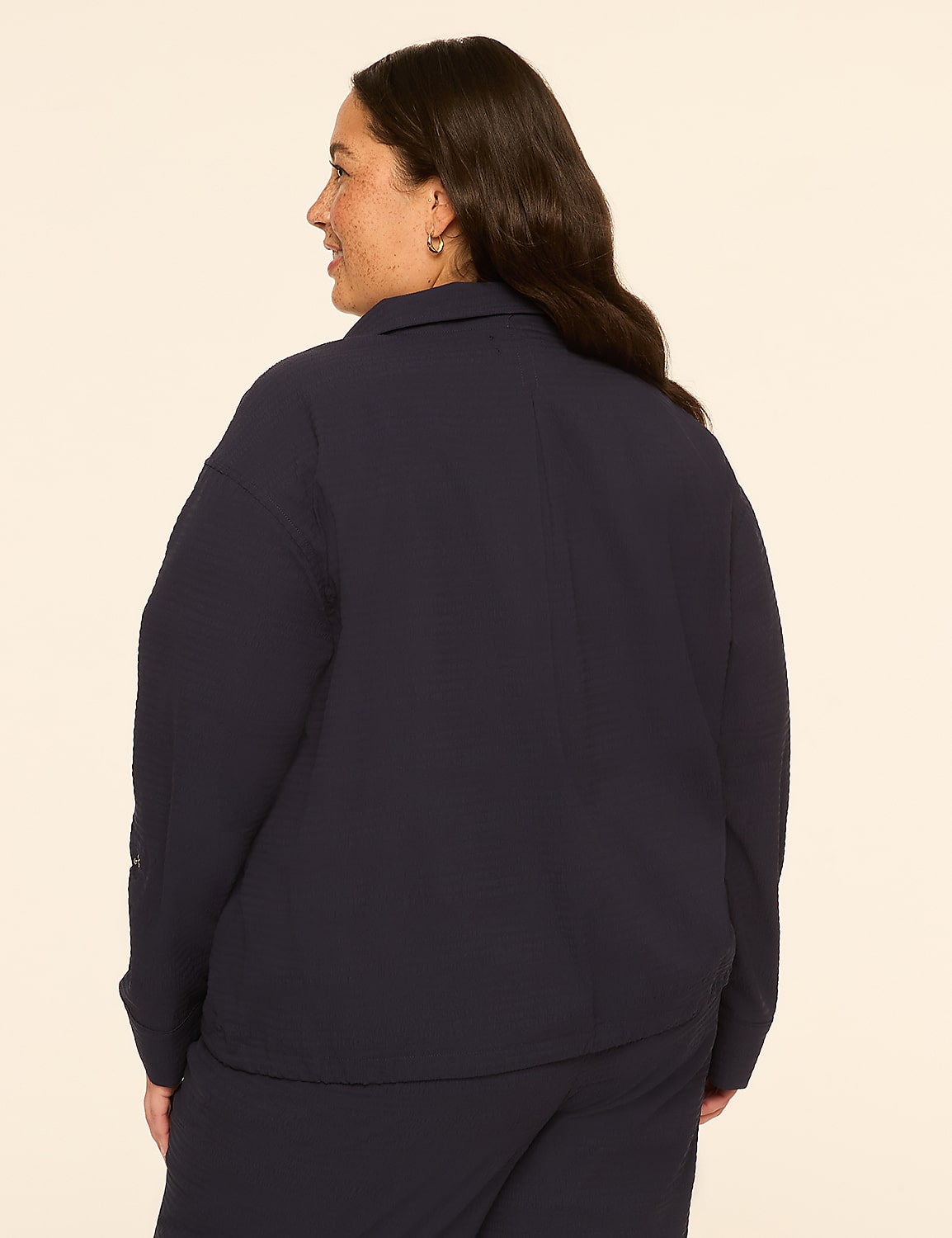 A woman in a navy blue collared shirt and pants stands against a plain cream background. Product Image 2