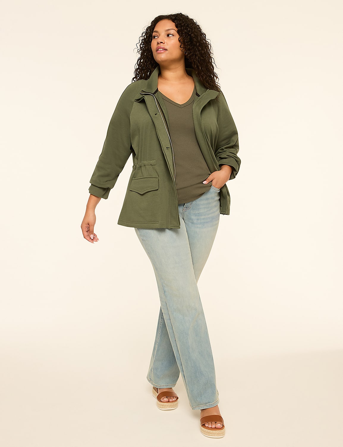 A woman in a green jacket and jeans walks against a plain, light-colored background. Product Image 3