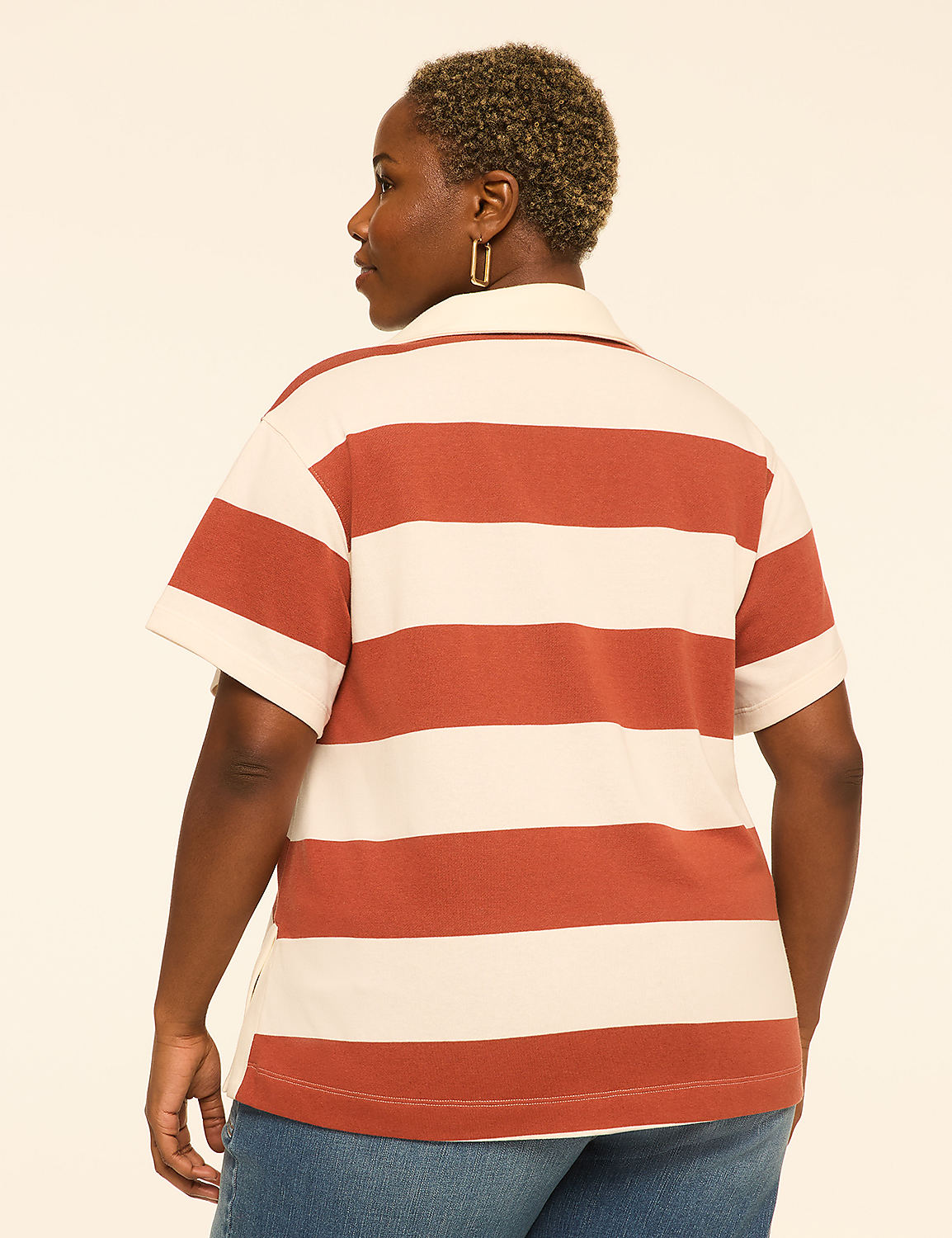 A woman with short, blonde hair wears a striped polo shirt and jeans, standing against a plain, light-colored background. Product Image 2