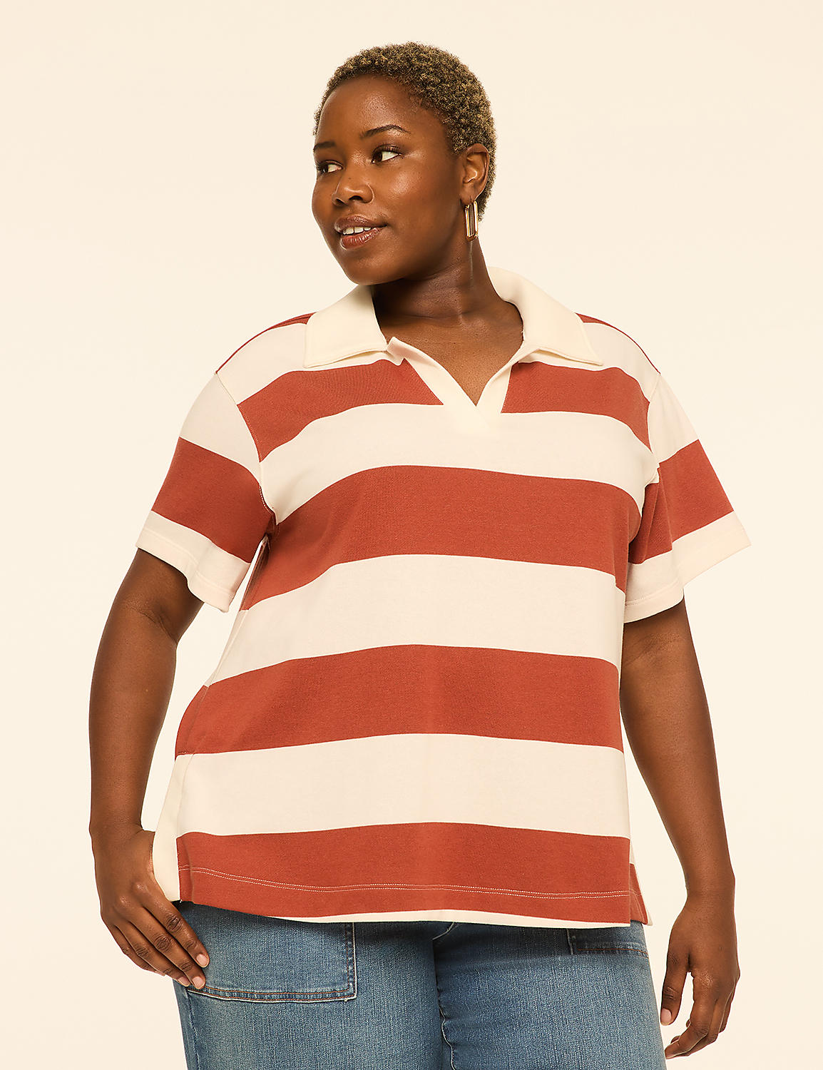 A woman in a striped polo shirt and denim jeans stands against a plain, light-colored background. Product Image 1