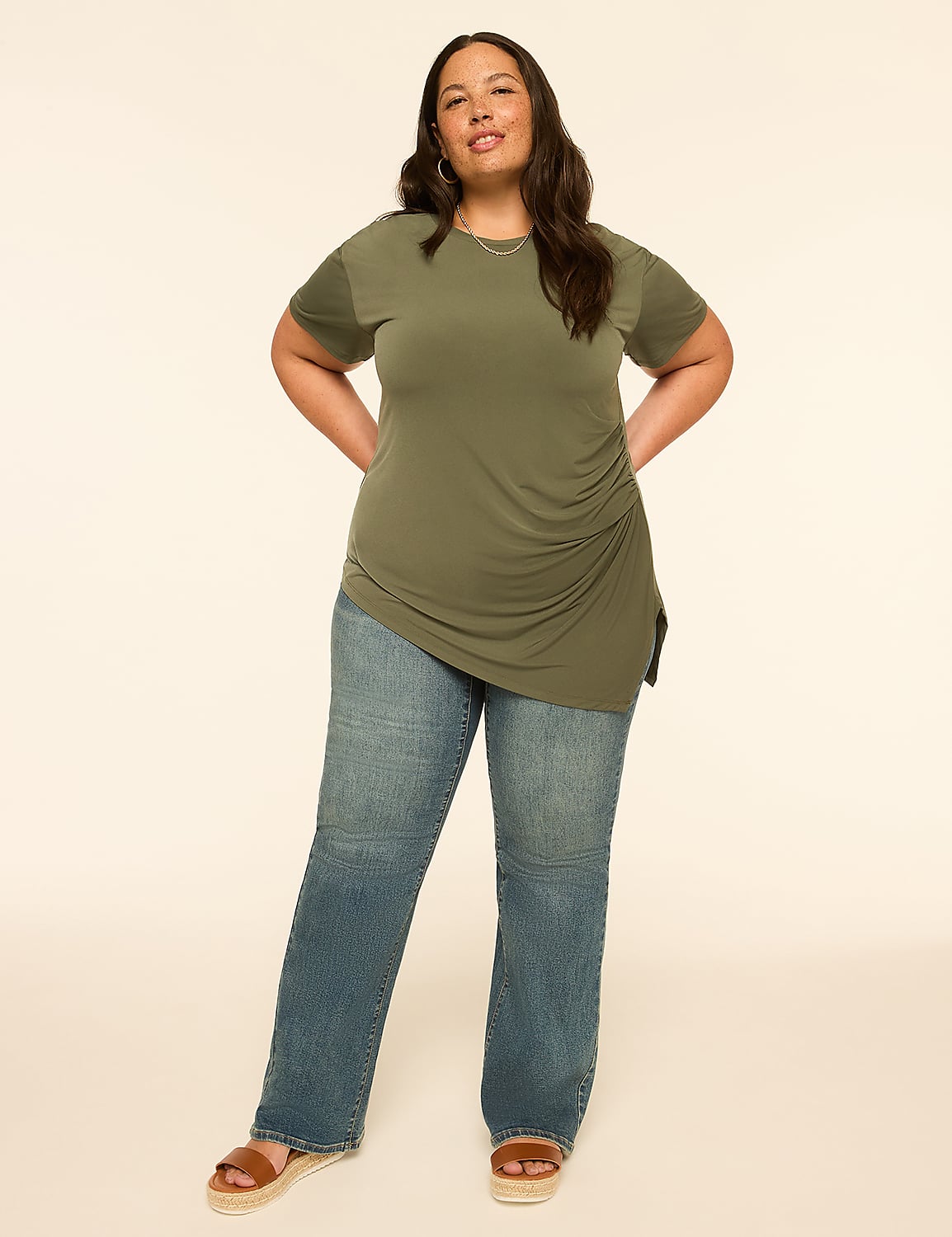 A woman in a green ruched top and blue jeans stands against a plain, light-colored background. Product Image 3