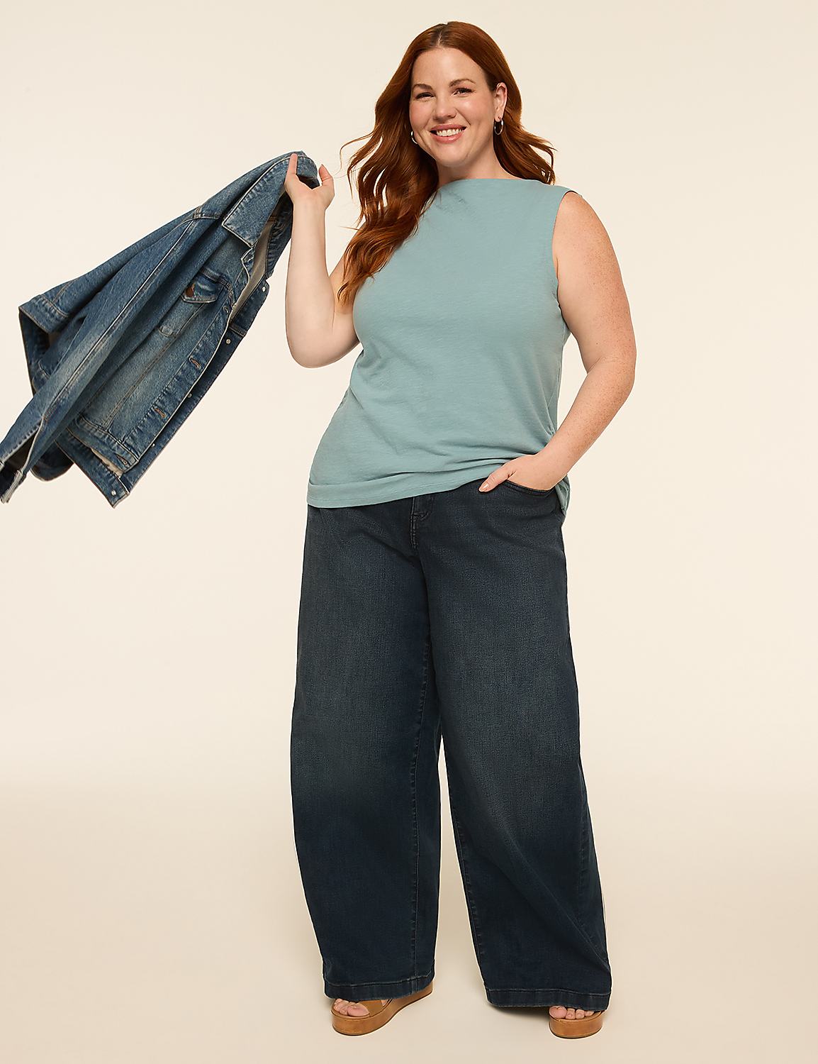 A smiling woman with red hair stands in the foreground holding a denim jacket, against a plain, light-colored background. Product Image 3