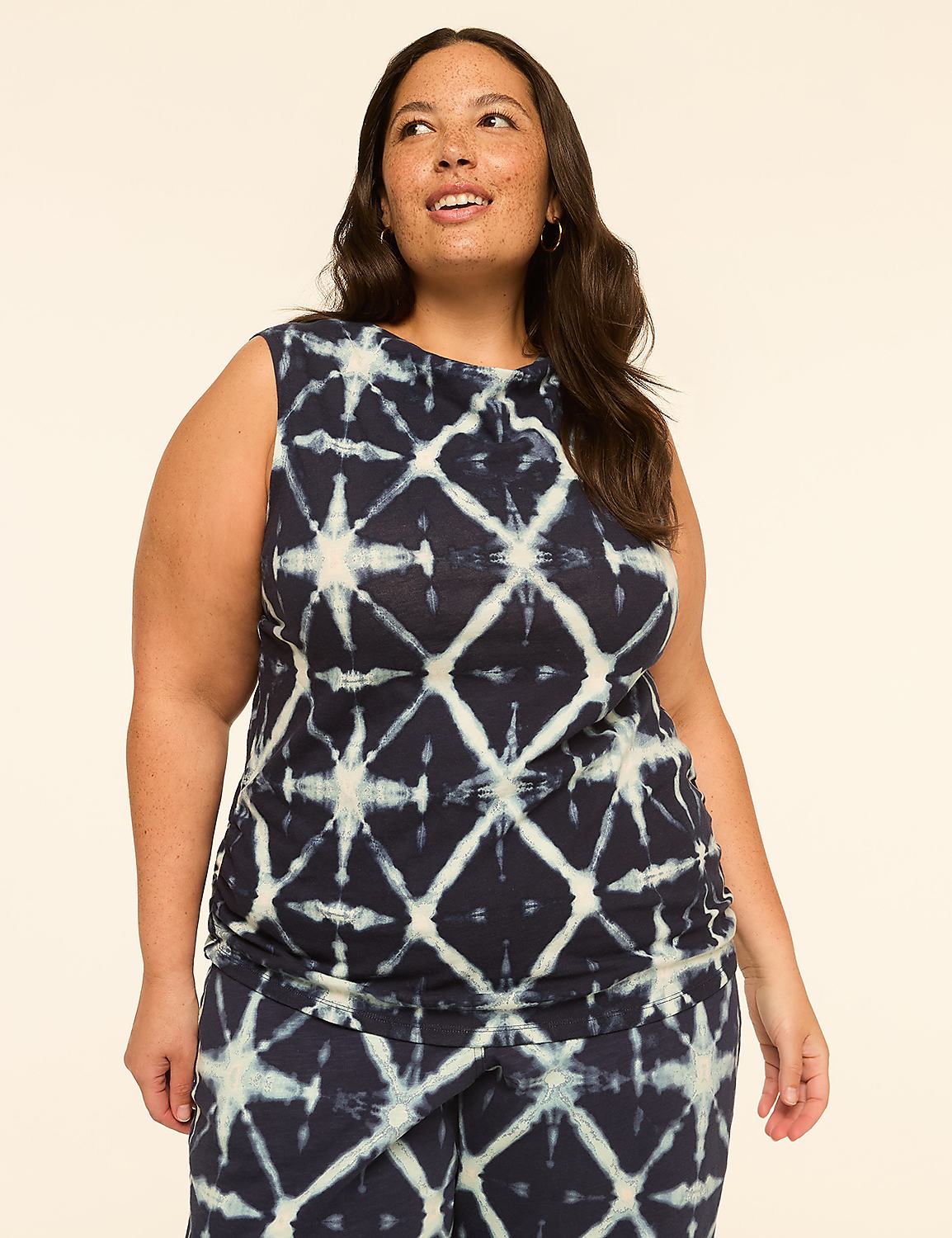 A woman with dark hair and freckles poses in a tie-dye top against a plain, light-colored background. Product Image 1