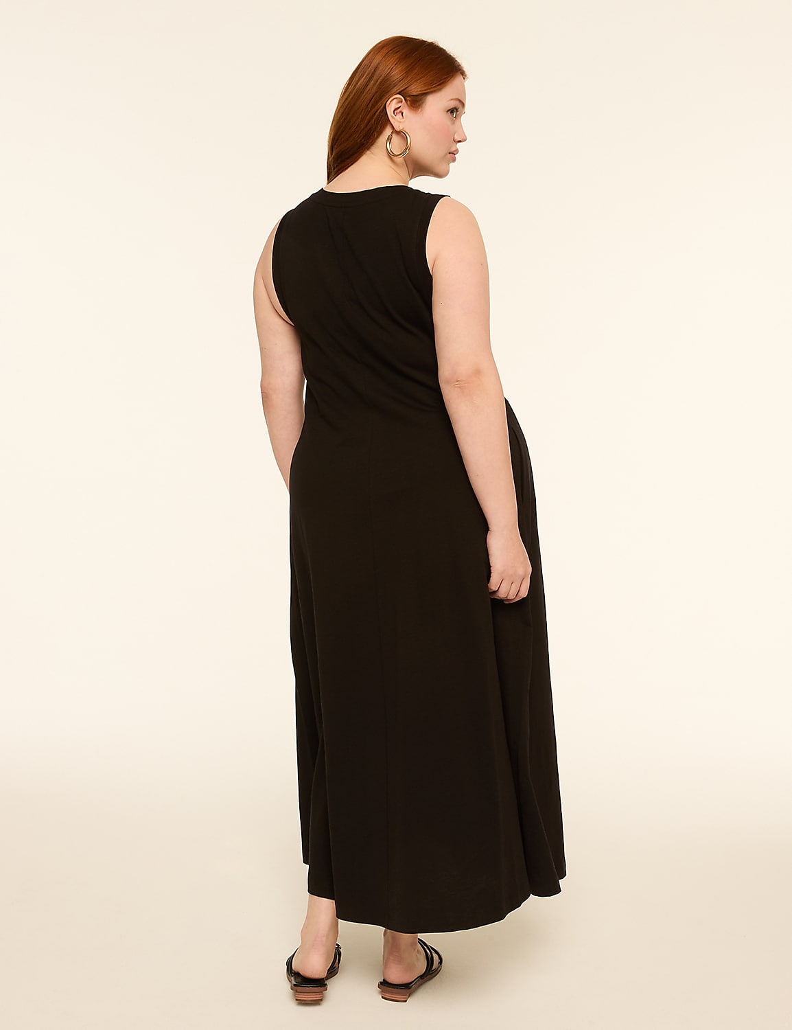 A woman with red hair wearing a black sleeveless dress and sandals stands against a plain, light-colored background. Product Image 2