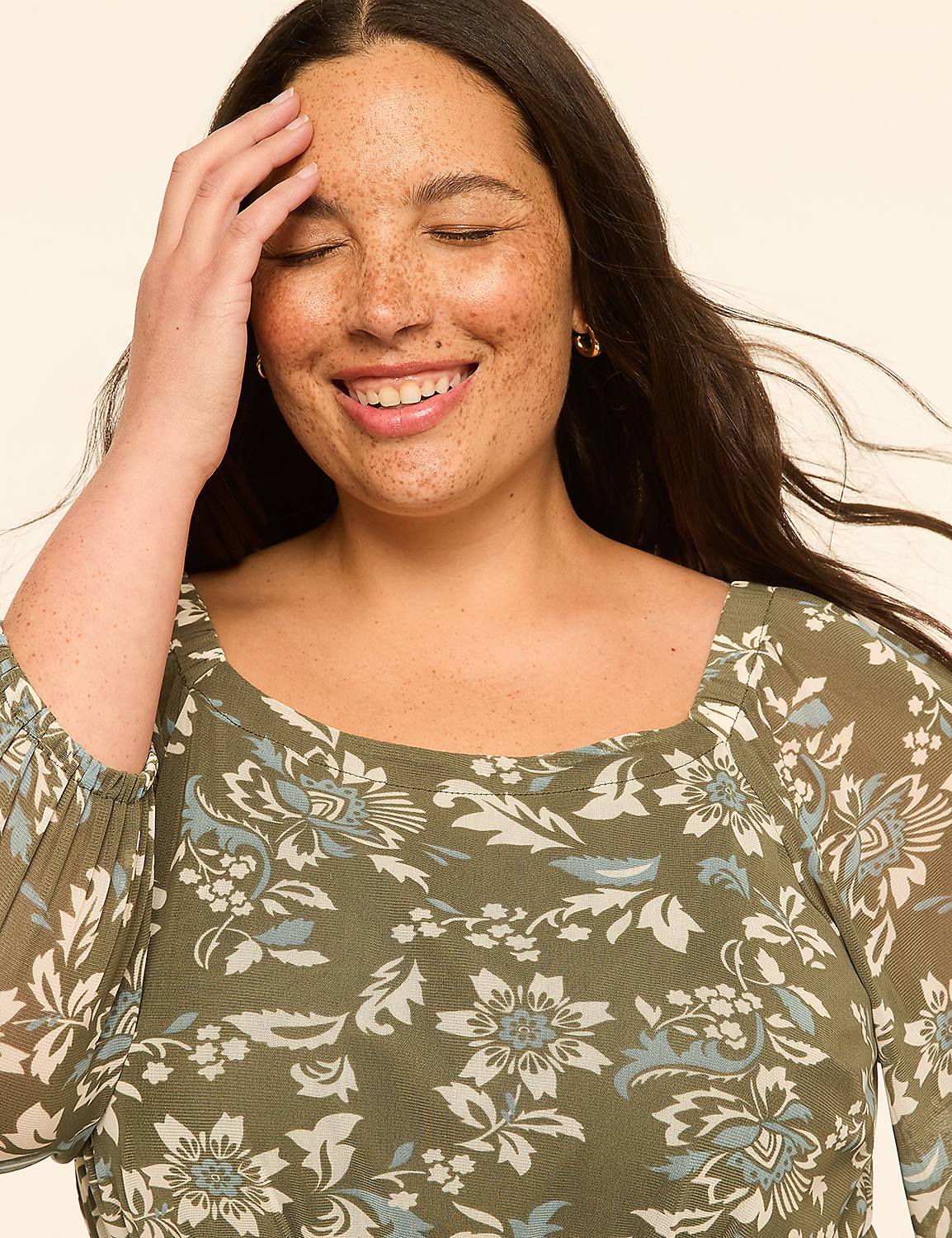 A smiling woman with freckles and her hand on her forehead wears a floral print top against a plain, light-colored background. Product Image 3