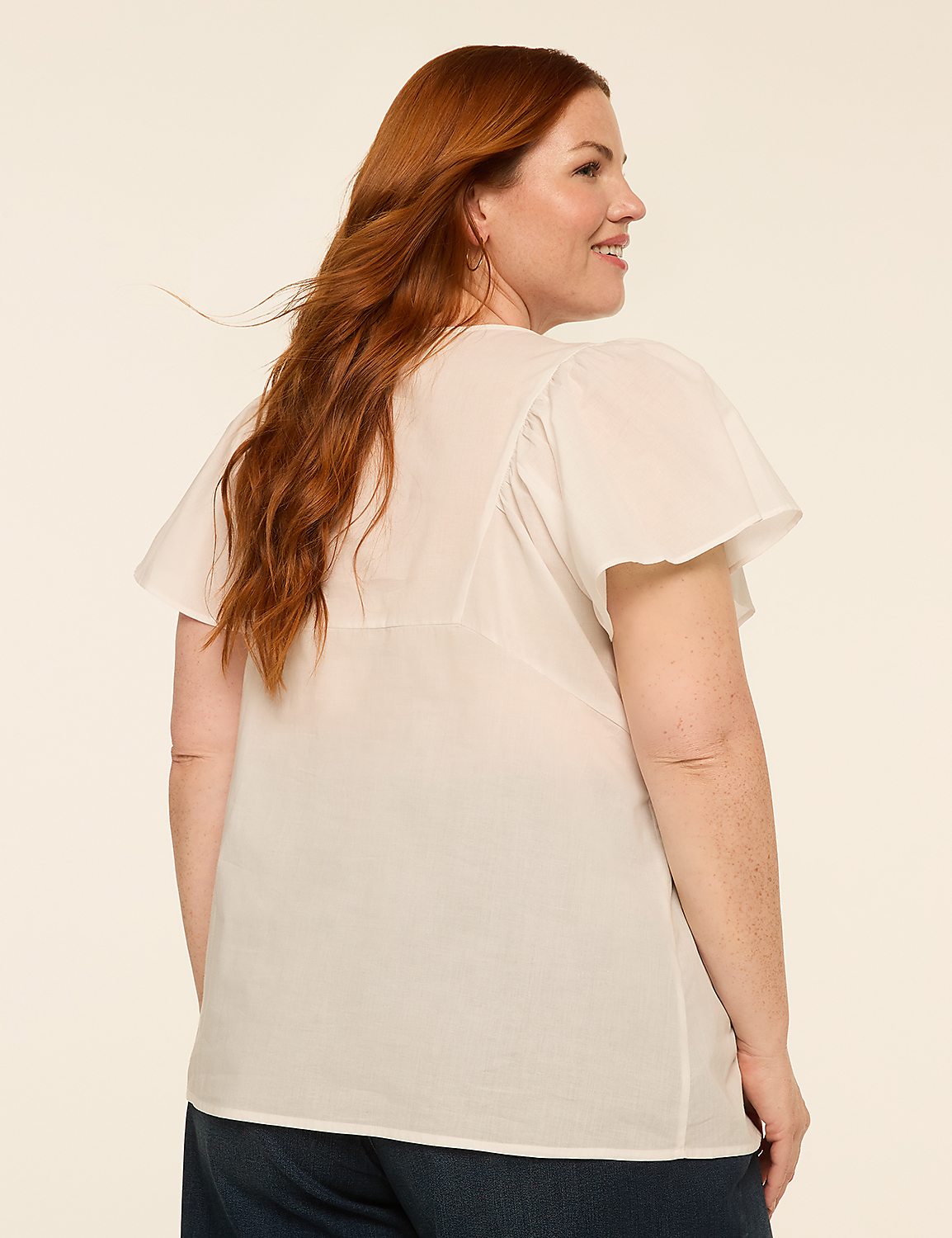 A woman with red hair wearing a white top and dark pants stands against a plain, light-colored background. Product Image 2