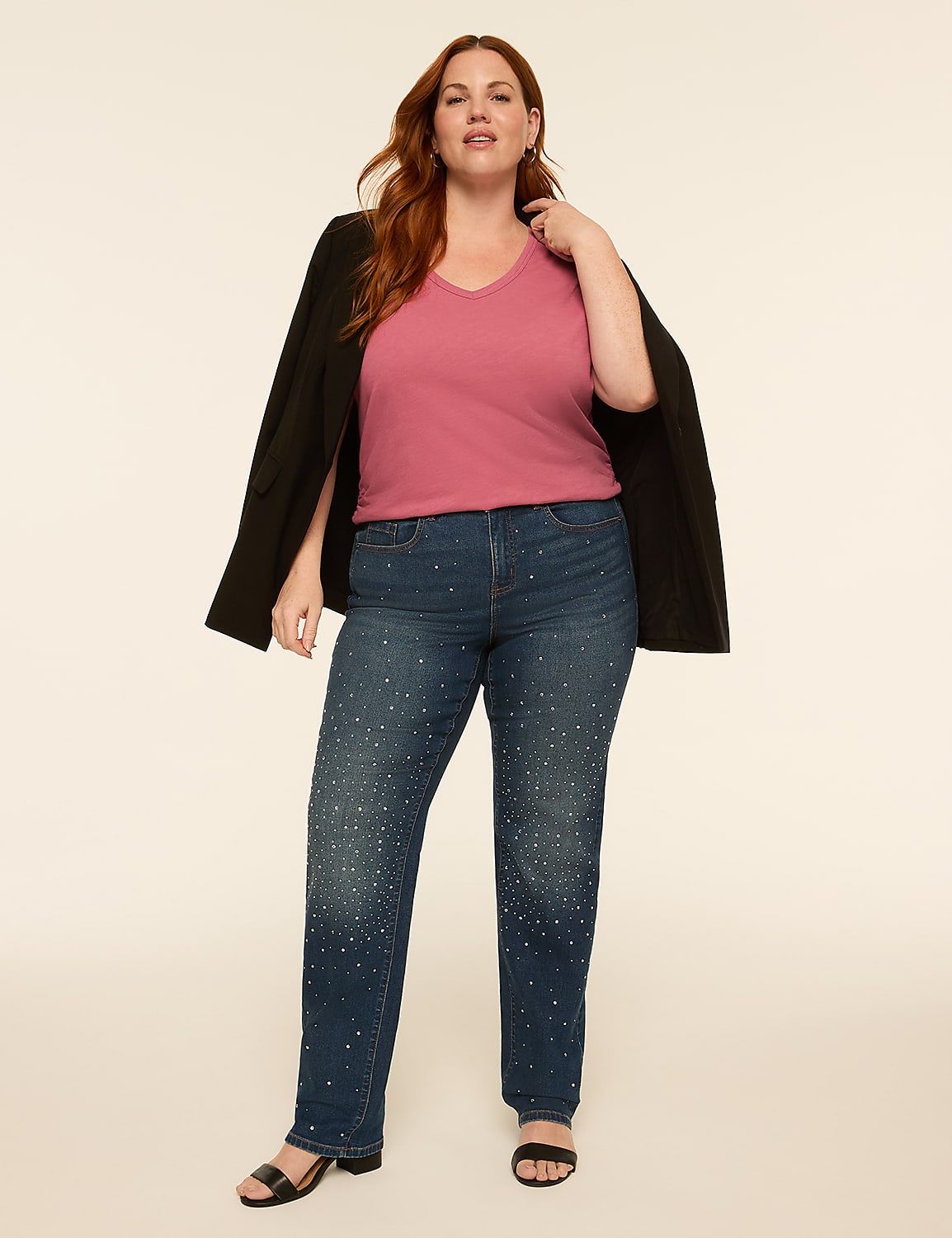 A woman in a pink v-neck shirt, a black blazer draped over her shoulders, and embellished denim jeans stands against a plain, light-colored background. Product Image 3