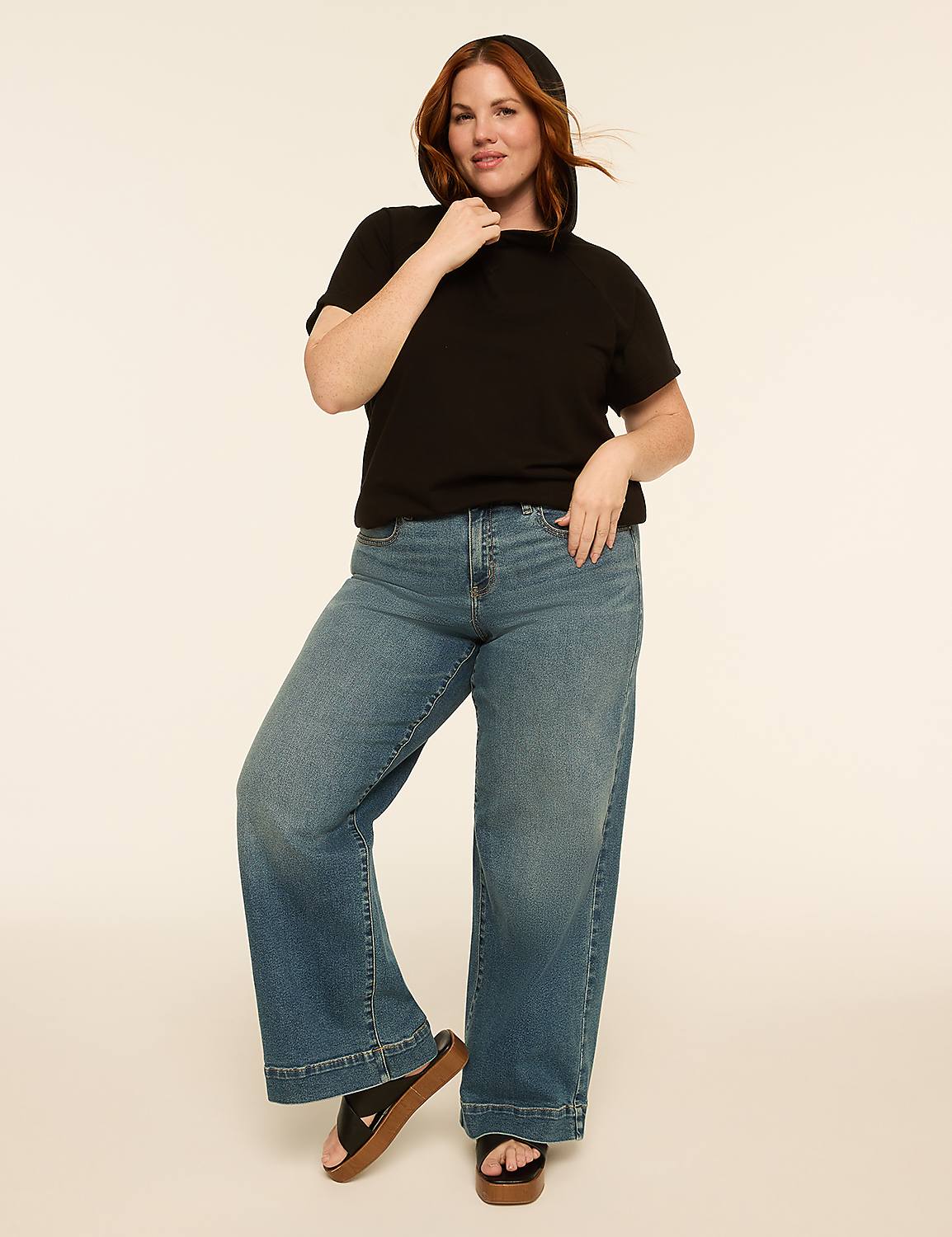 A woman in a black t-shirt and wide-leg jeans poses against a plain, light-colored background. Product Image 3