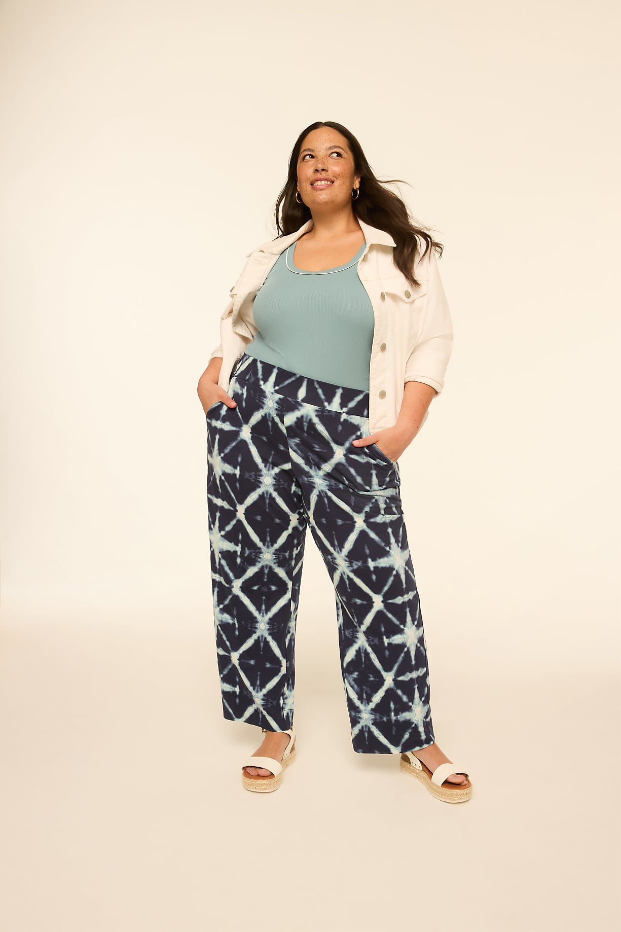 A woman in a patterned outfit stands with her hands in her pockets against a plain, light-colored background. Product Image 4