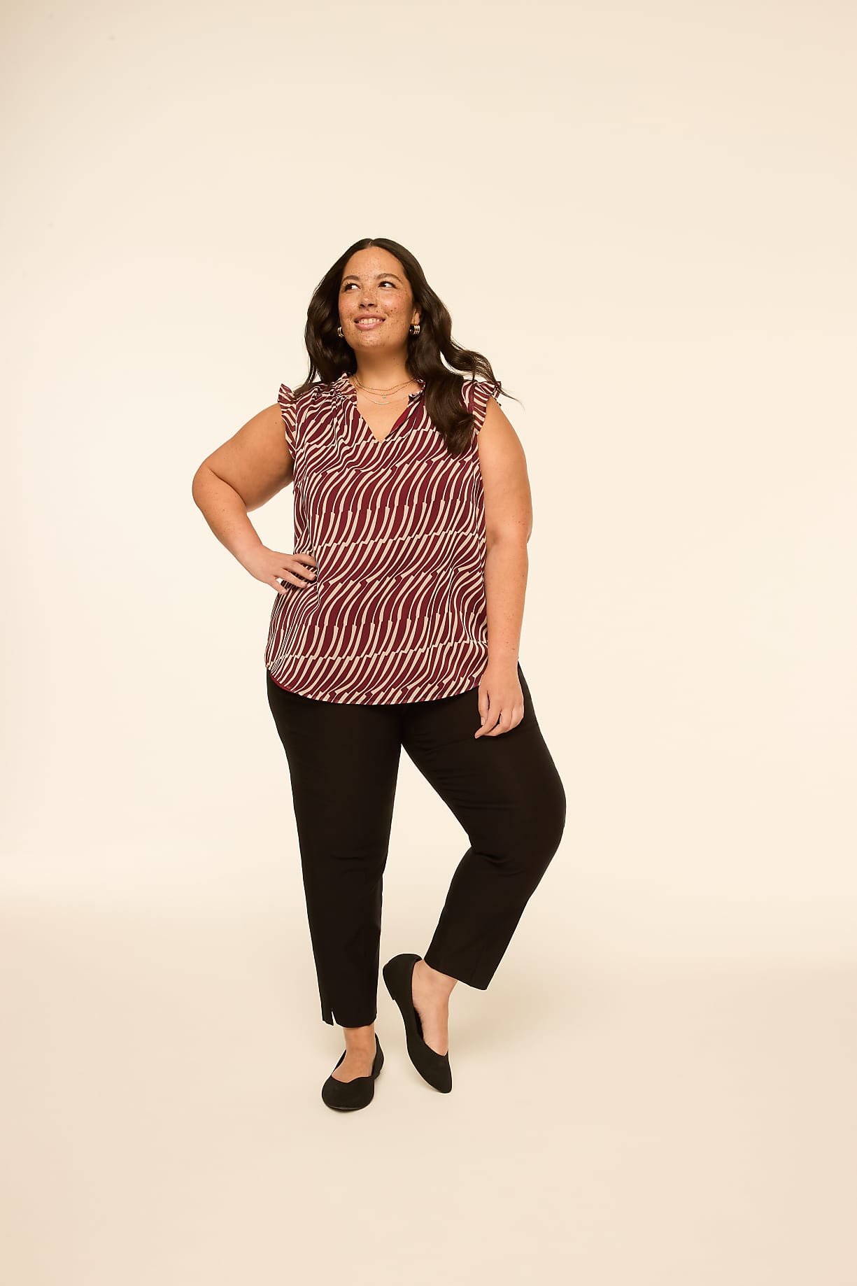 A woman in a patterned top and black pants stands against a plain, light-colored background. Product Image 4