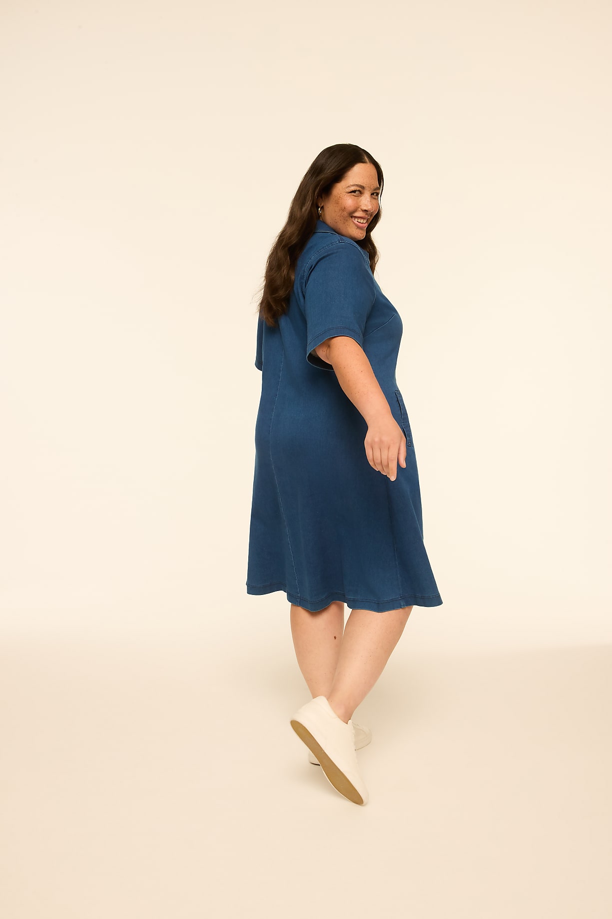 A woman in a blue dress and white shoes poses against a plain, light-colored background. Product Image 4