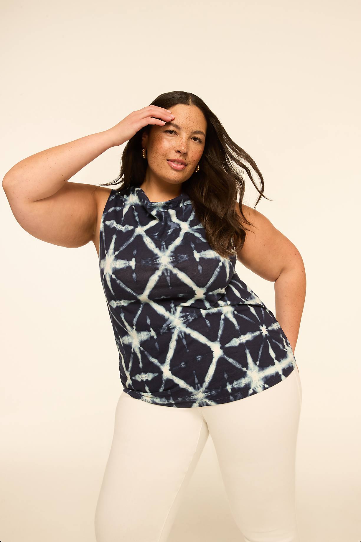 A woman in a tie-dye top and white pants poses against a plain, light-colored background. Product Image 5