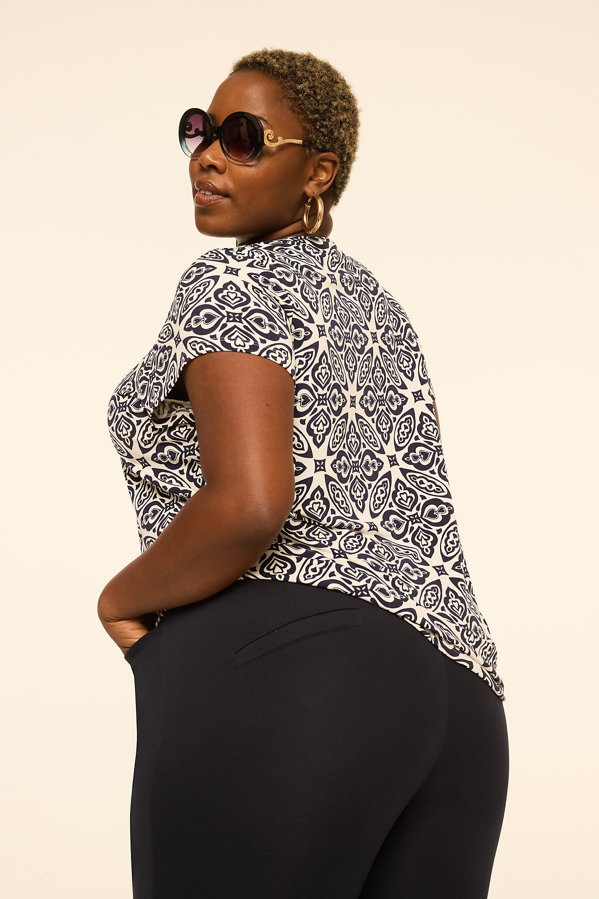 A woman with short, blonde hair and sunglasses poses with her hands in her pockets against a plain, light-colored background. Product Image 5