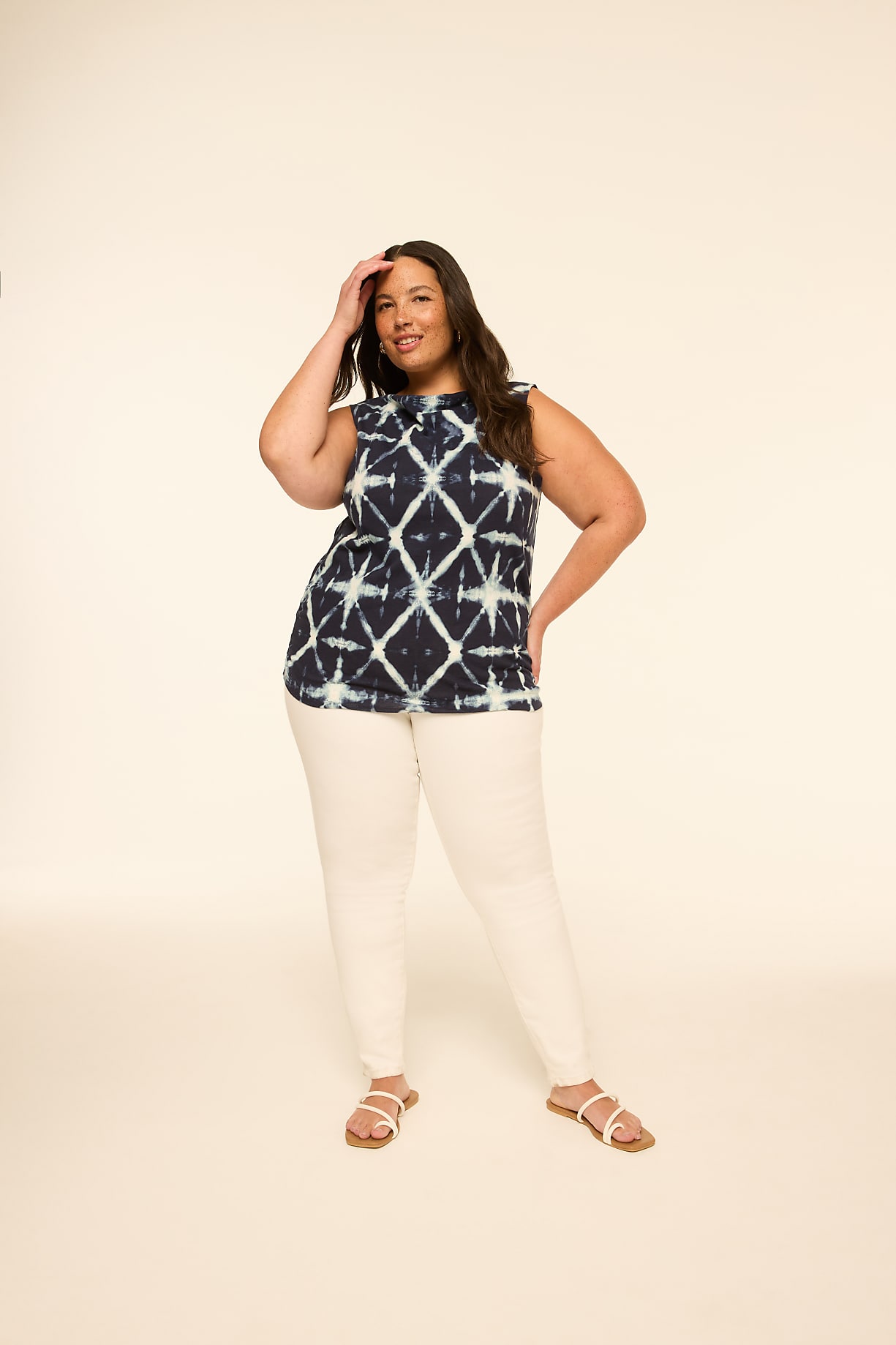 A woman in a tie-dye top and white pants stands against a plain, light-colored background. Product Image 7
